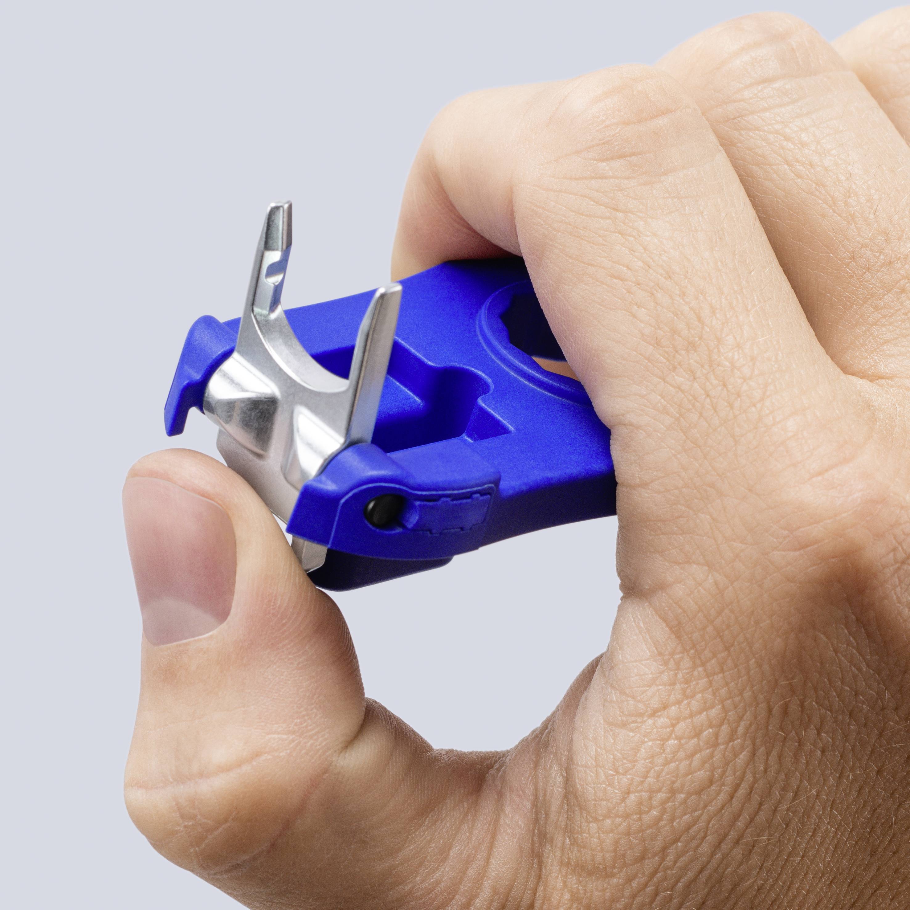 Una mano che tiene un tagliaunghie blu, con il pollice che preme la leva per tagliare le unghie.