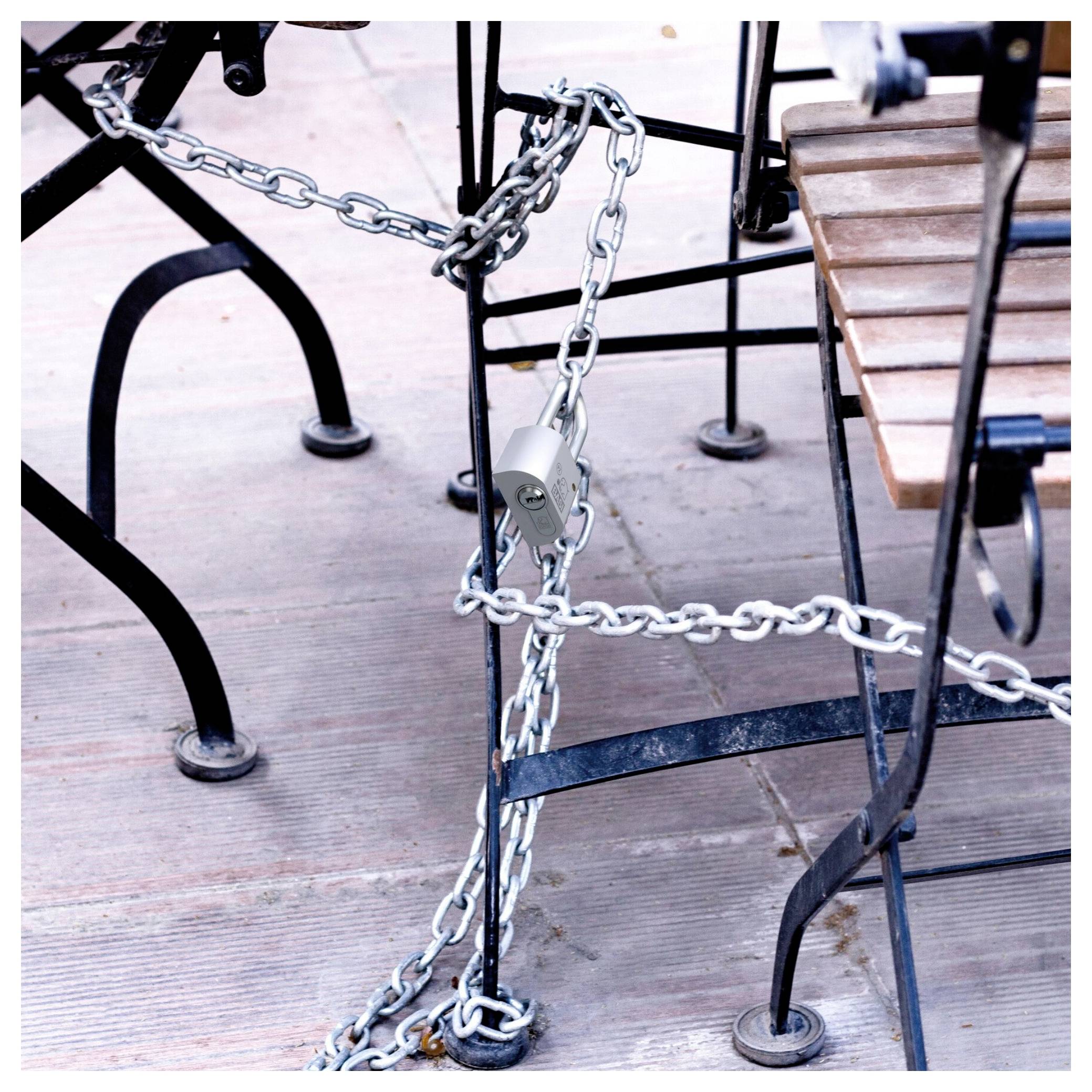Catena con lucchetto che protegge i mobili da esterno del patio, bloccando l'accesso a un tavolo e a delle sedie.
