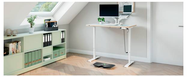 Angolo home office con una scrivania regolabile in altezza, monitor e laptop, un mobile di stoccaggio e una tastiera sul pavimento sotto la scrivania.