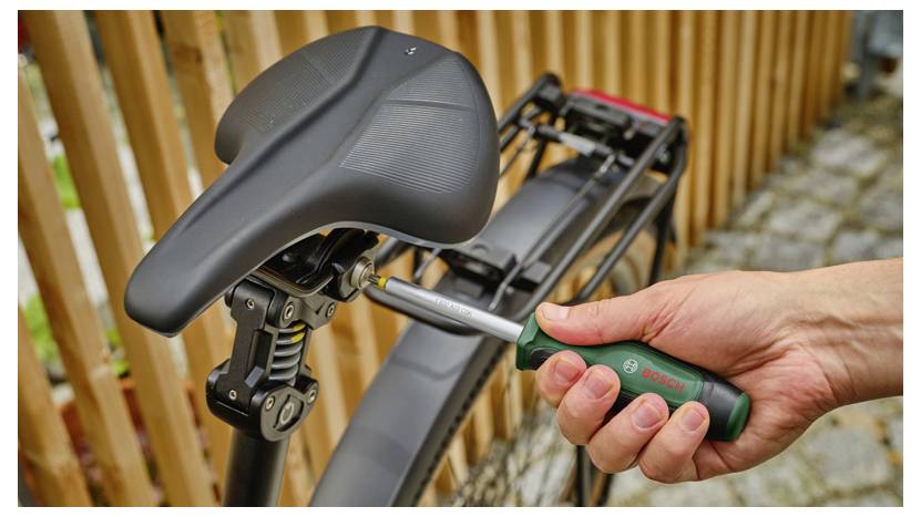 Operaio con equipaggiamento di sicurezza utilizza una smerigliatrice portatile o un trapano per tagliare una parete in calcestruzzo, creando polvere durante i lavori di costruzione.