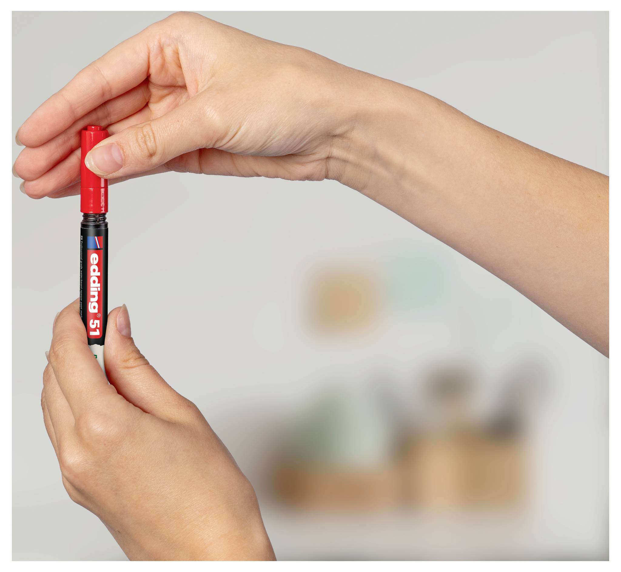 Mani che tengono una penna pennarello Edding 51 rossa verticalmente, mostrando il tappo e l'etichetta della penna.