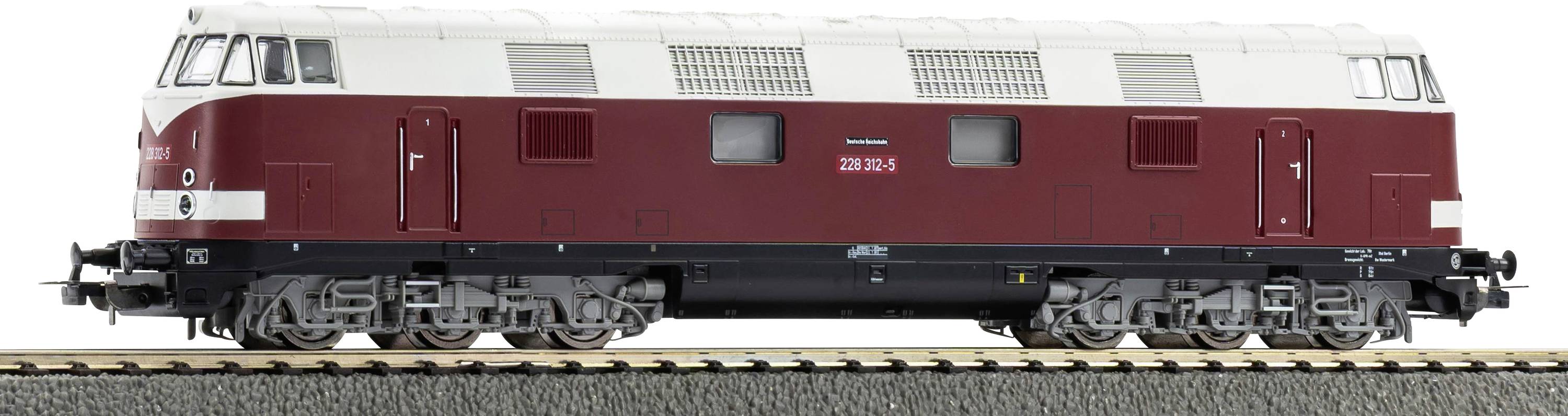 Vista laterale di una locomotiva diesel marrone e color crema sui binari, mostrata su uno sfondo bianco uniforme.