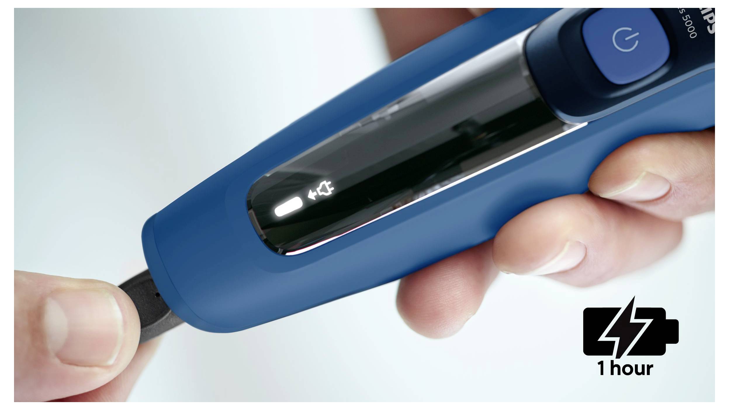 Mano che tiene un glucometro blu con una striscia reattiva inserita, che mostra un'icona della batteria e un indicatore di carica '1 ora'.
