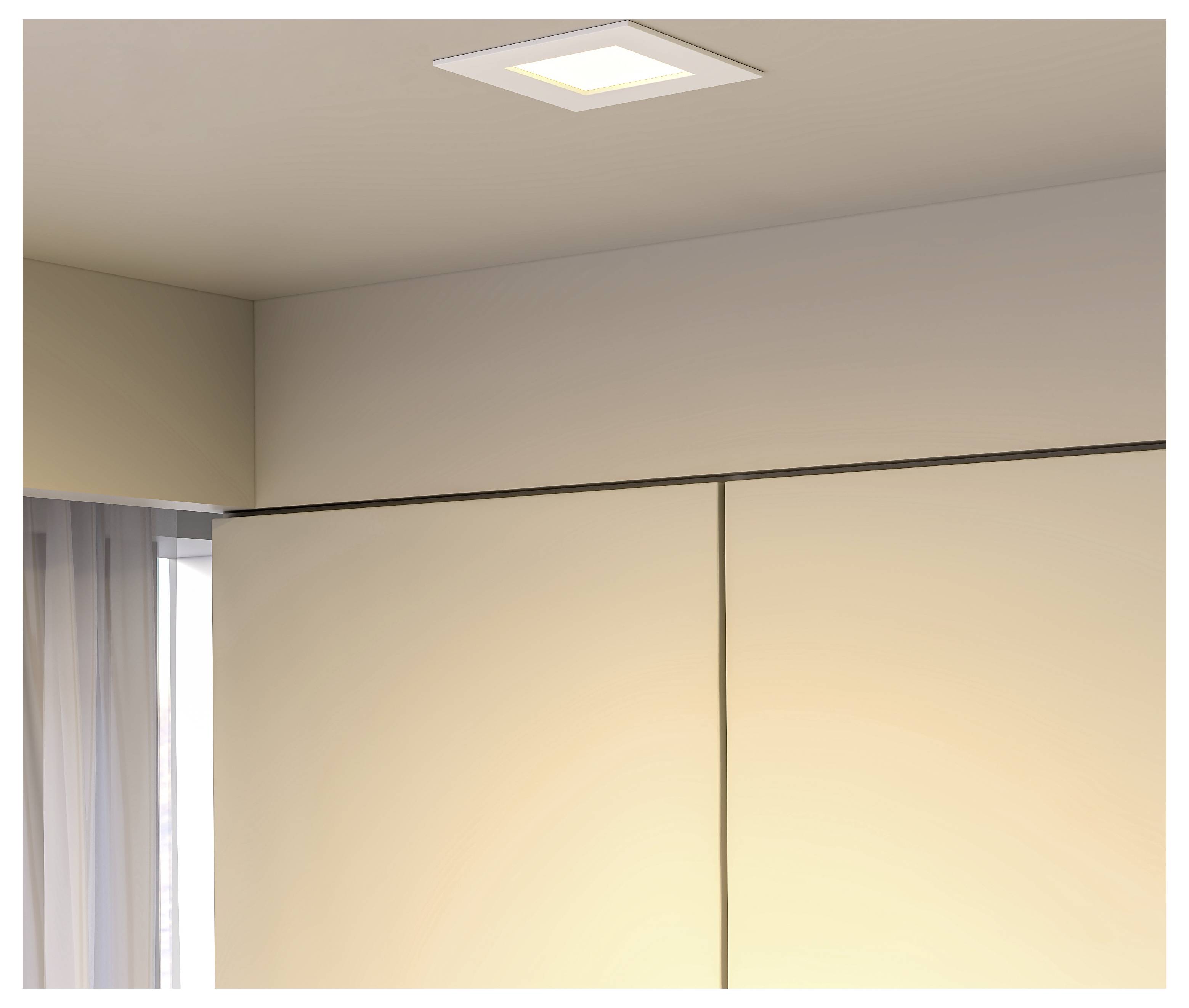 Luce al soffitto sopra pareti beige e una finestra con tende trasparenti in una stanza minimalista.