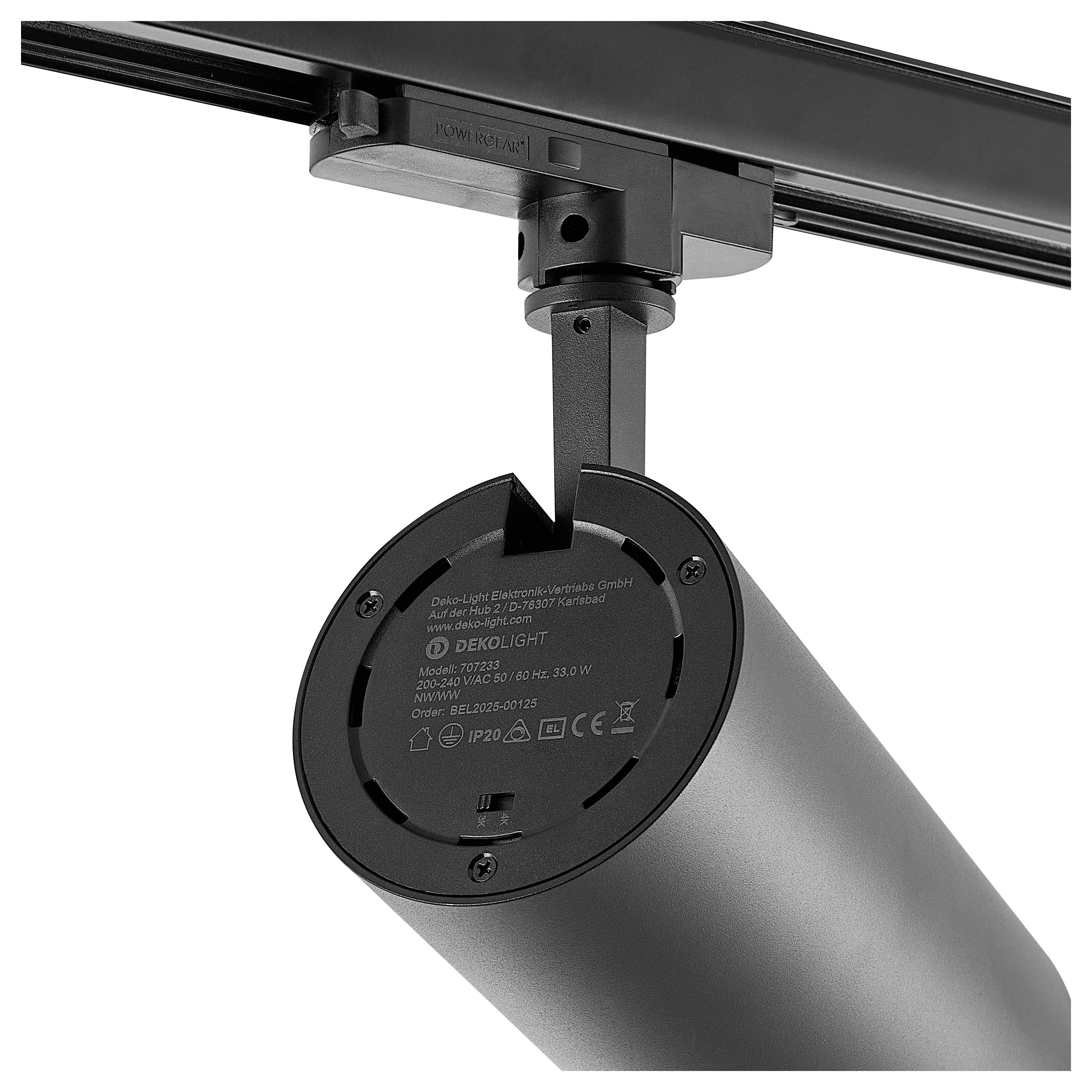 Faretto cilindrico nero montato su binario a soffitto, visualizzato da sotto con il suo supporto regolabile e l'etichetta visibili.