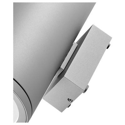 Primo piano di un apparecchio di illuminazione argentato montato a parete attaccato a una superficie metallica curva su uno sfondo bianco.