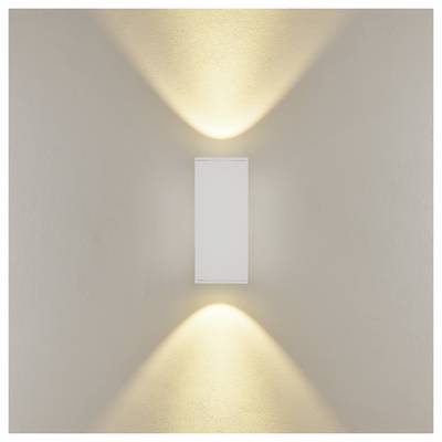 Lampada rettangolare a parete che proietta fasci di luce calda verso l'alto e verso il basso su una parete beige.
