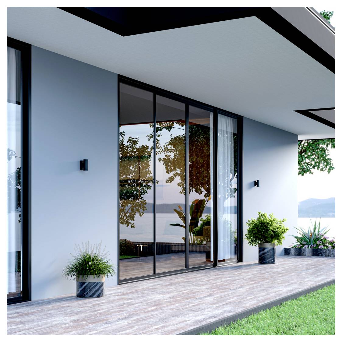Patio di una casa moderna con porte in vetro da pavimento a soffitto, pareti azzurro chiaro, piante in vaso, terrazza in legno e prato con vista su acqua e colline.