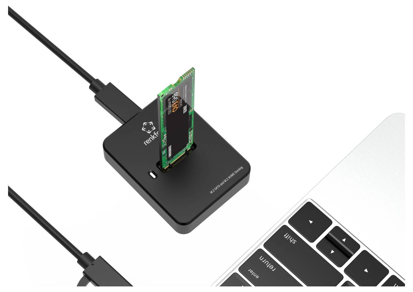 Un dispositivo USB nero con una scheda SD/microSD inserita si trova accanto alla tastiera di un laptop, mostrando un lettore di schede esterno collegato tramite cavo.