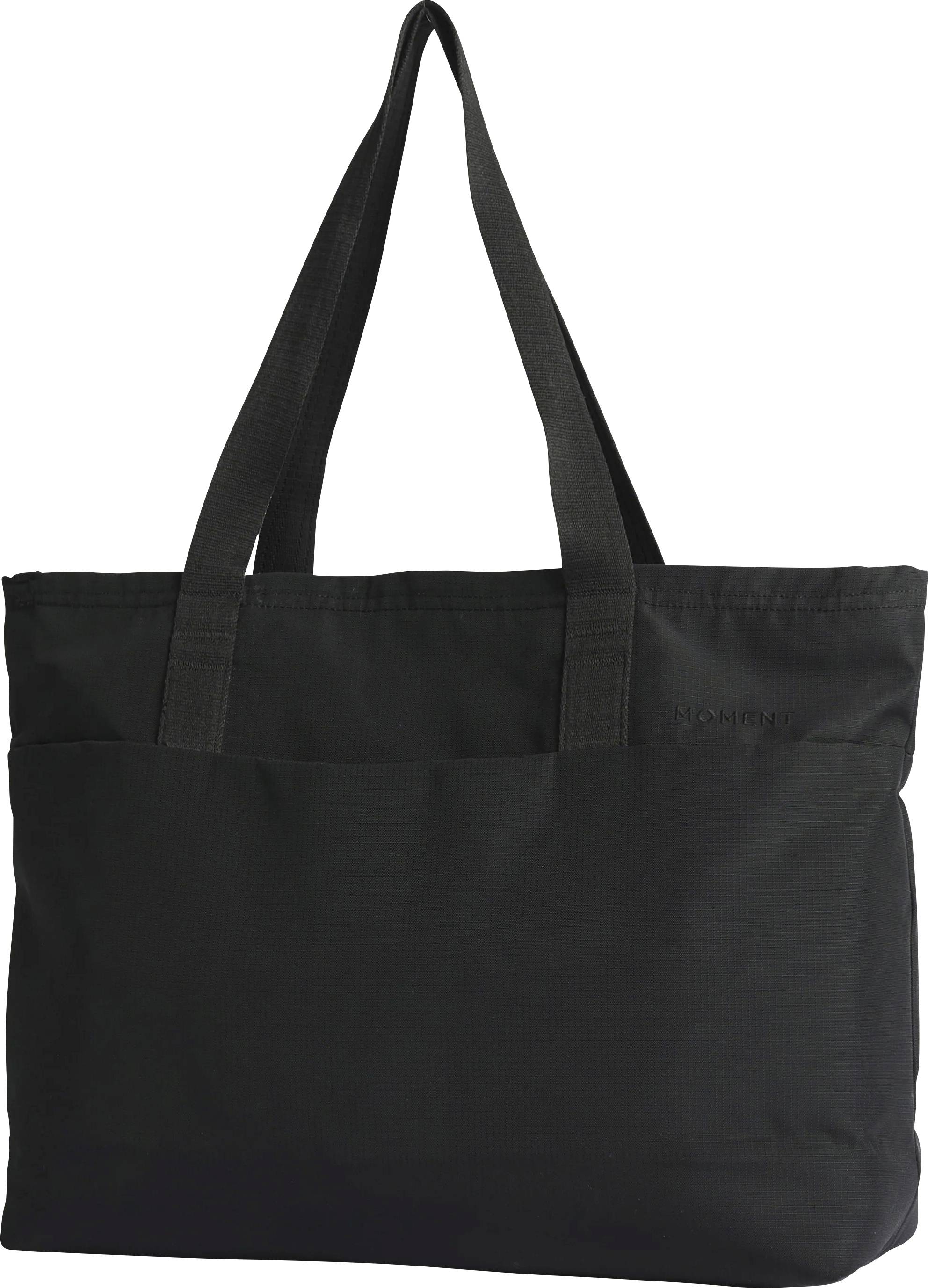 Borsa shopper nera con lunghe spallaccini e una tasca con cerniera sul davanti su sfondo bianco neutro.