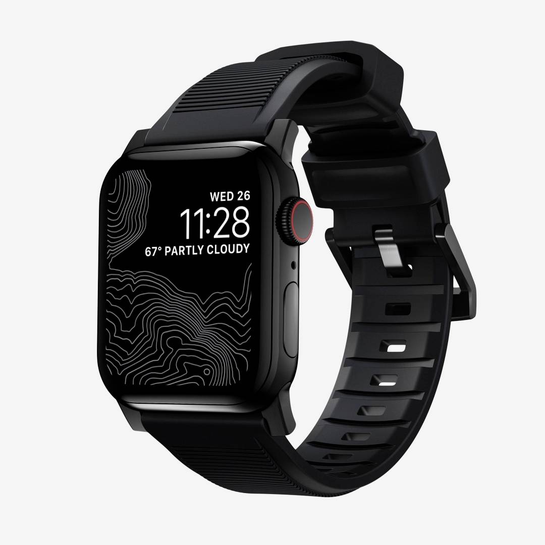 Smartwatch nero con display rettangolare che mostra 'MER 26', '11:28' e '67° PARZIALMENTE NUVOLOSO', fotografato su un cinturino nero su uno sfondo chiaro.