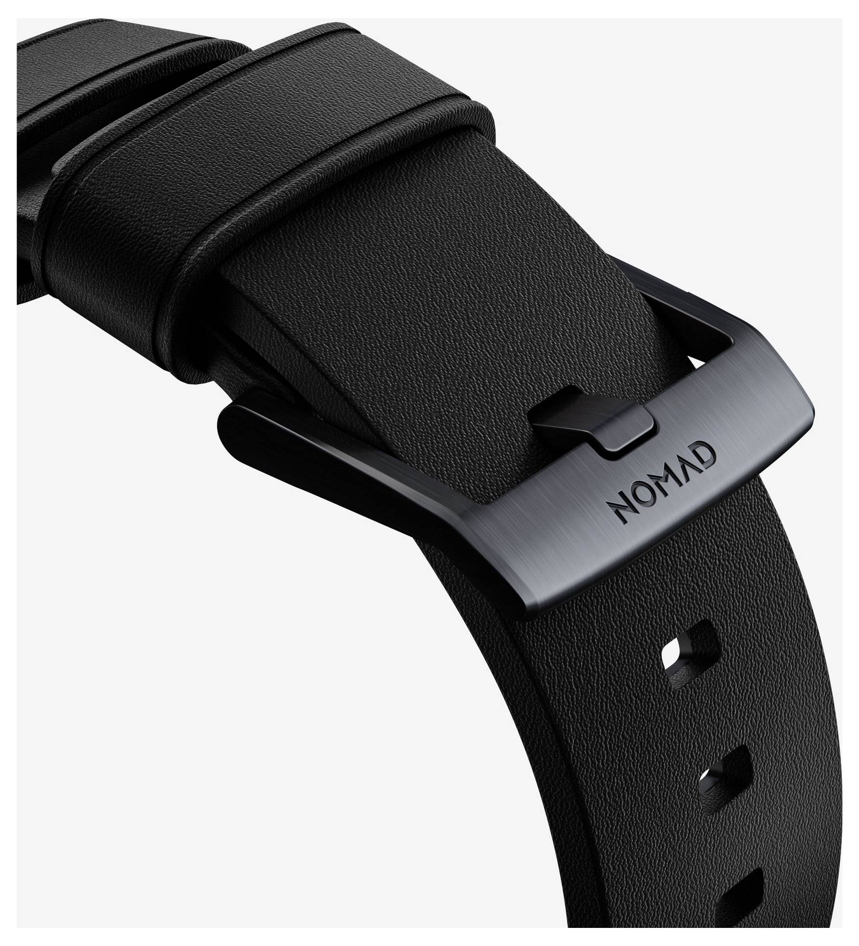 Cinturino per orologio in pelle nera con fibbia in metallo satinato incisa "NOMAD" su sfondo bianco.
