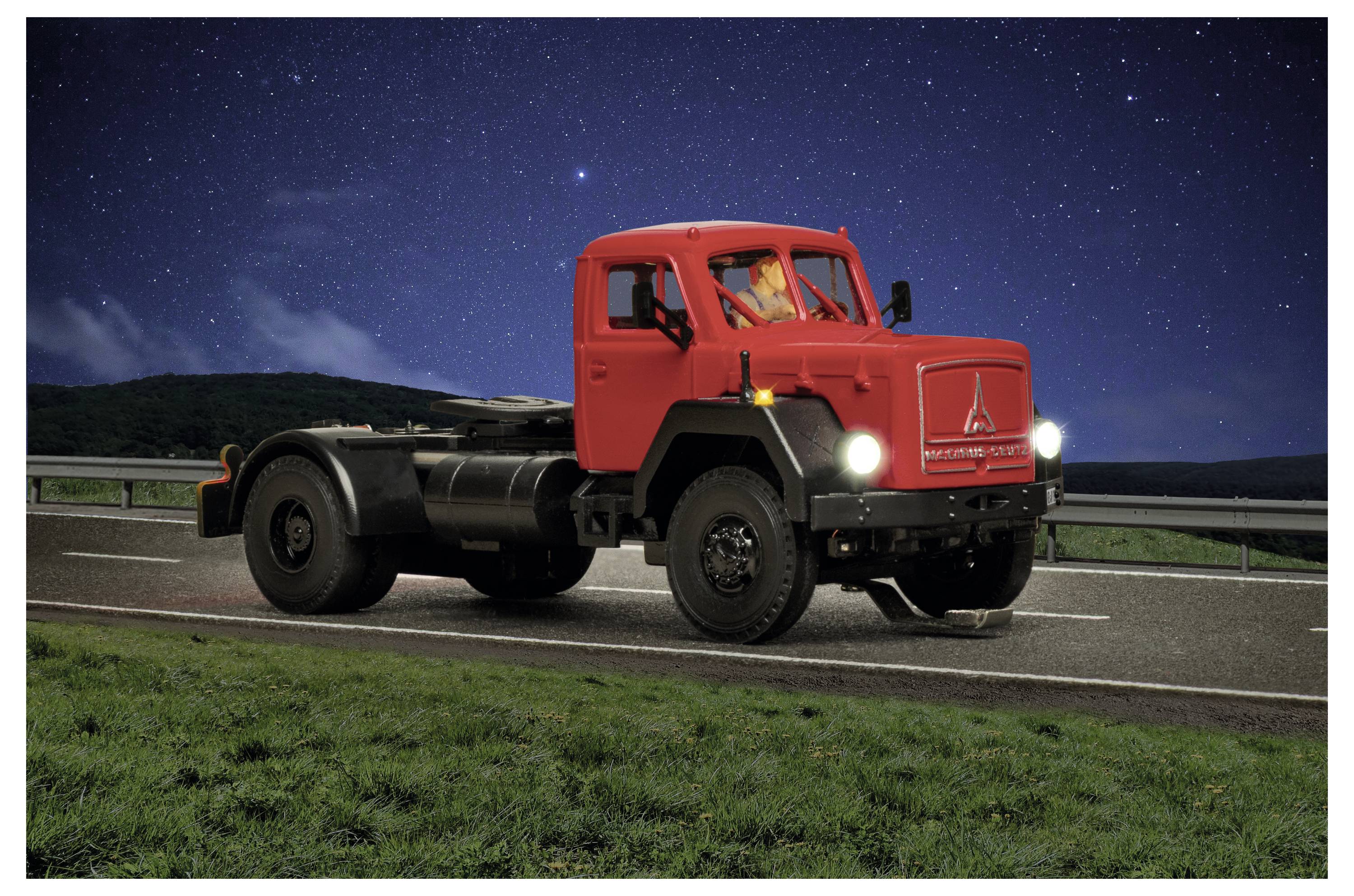 Camion d'epoca rosso che guida su un'autostrada di notte sotto un cielo stellato, con i fari accesi.