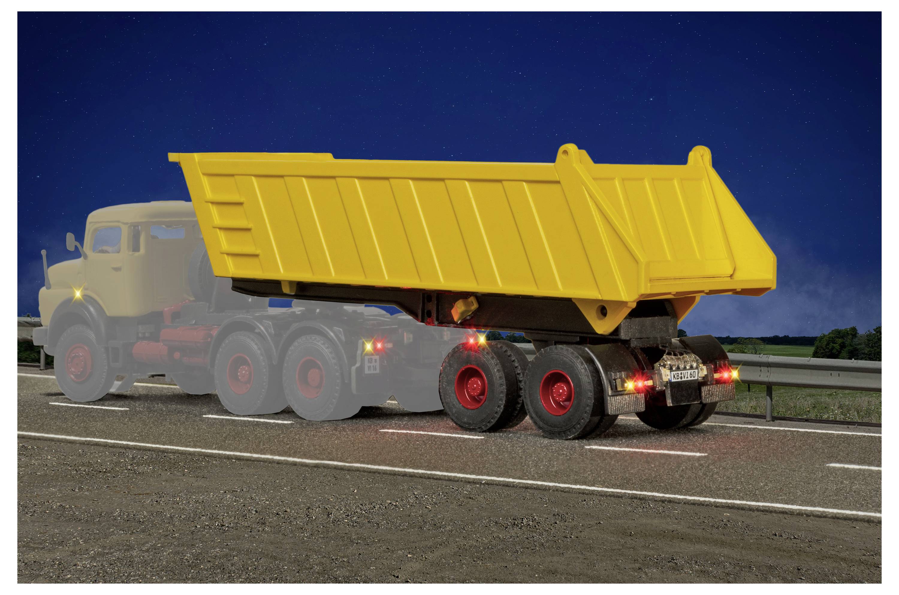 Rimorchio di camion ribaltabile giallo su un'autostrada al crepuscolo, con luci posteriori accese e una cabina beige parzialmente visibile attraverso la polvere o la nebbia.
