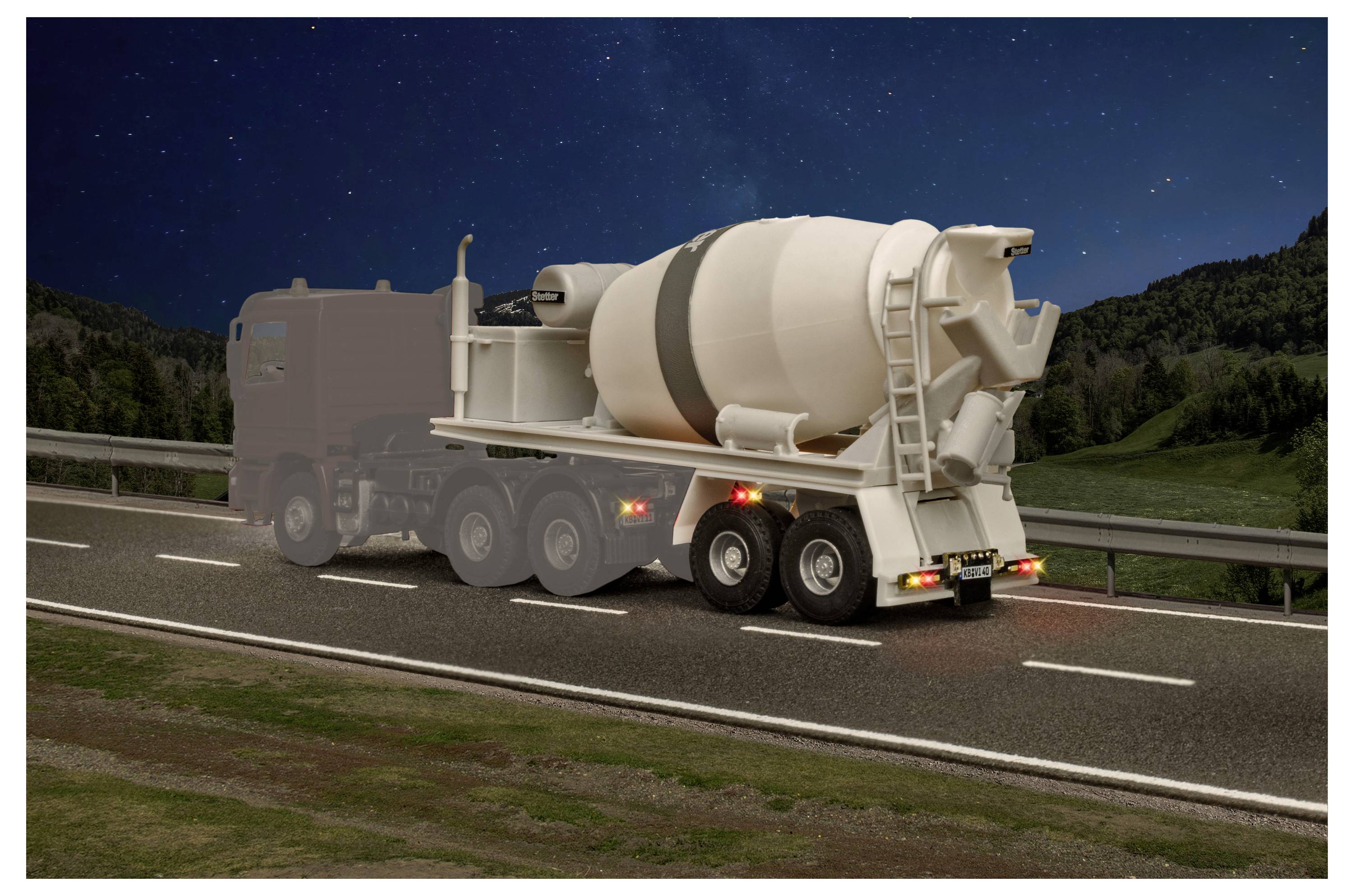 Un camion betoniera che guida su una strada di notte, visto da dietro con un cielo stellato e colline sullo sfondo.