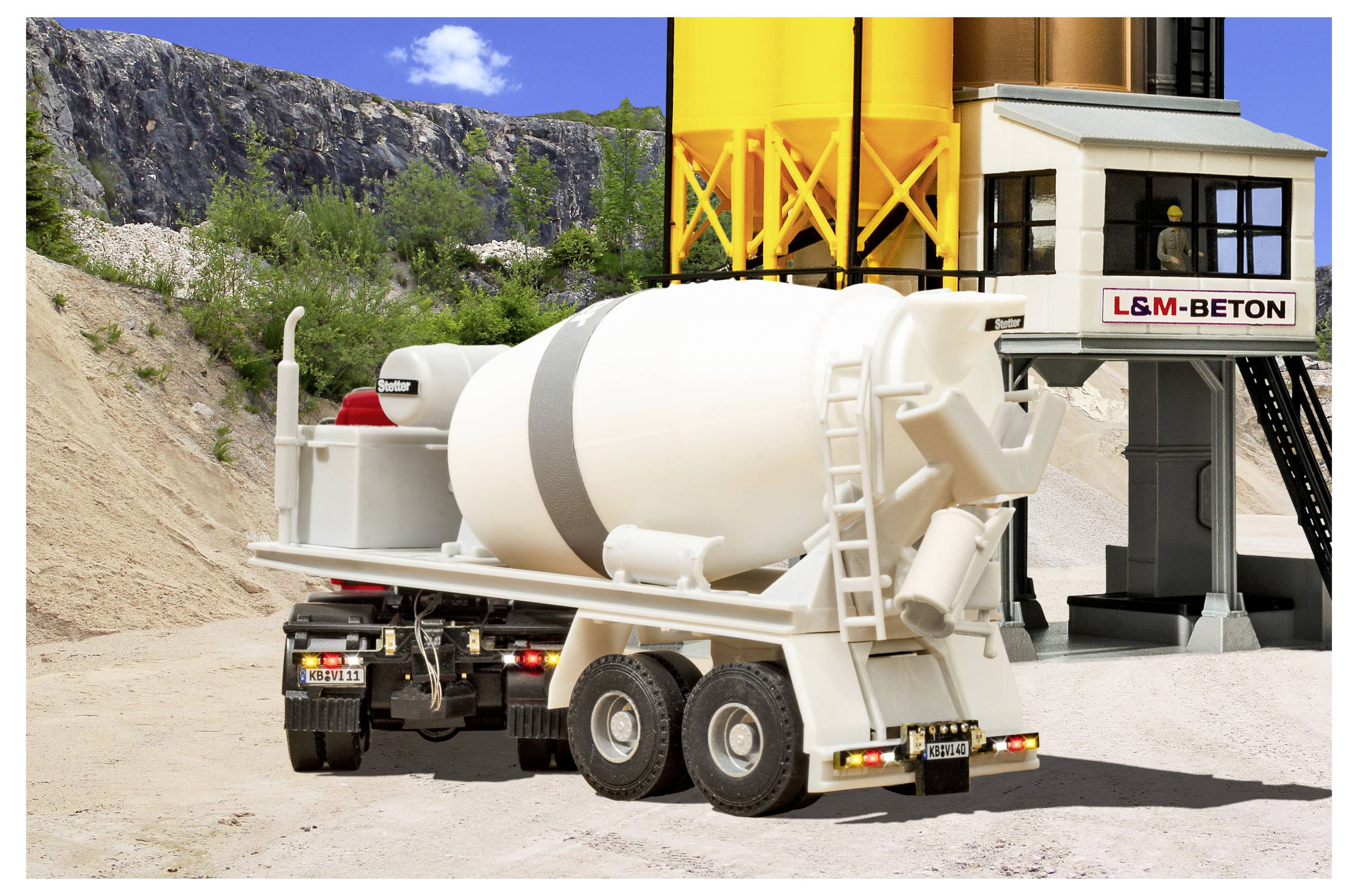 Camion betoniera presso uno stabilimento L&M-BETON accanto a silos gialli, con scogliere di cava rocciosa sullo sfondo.