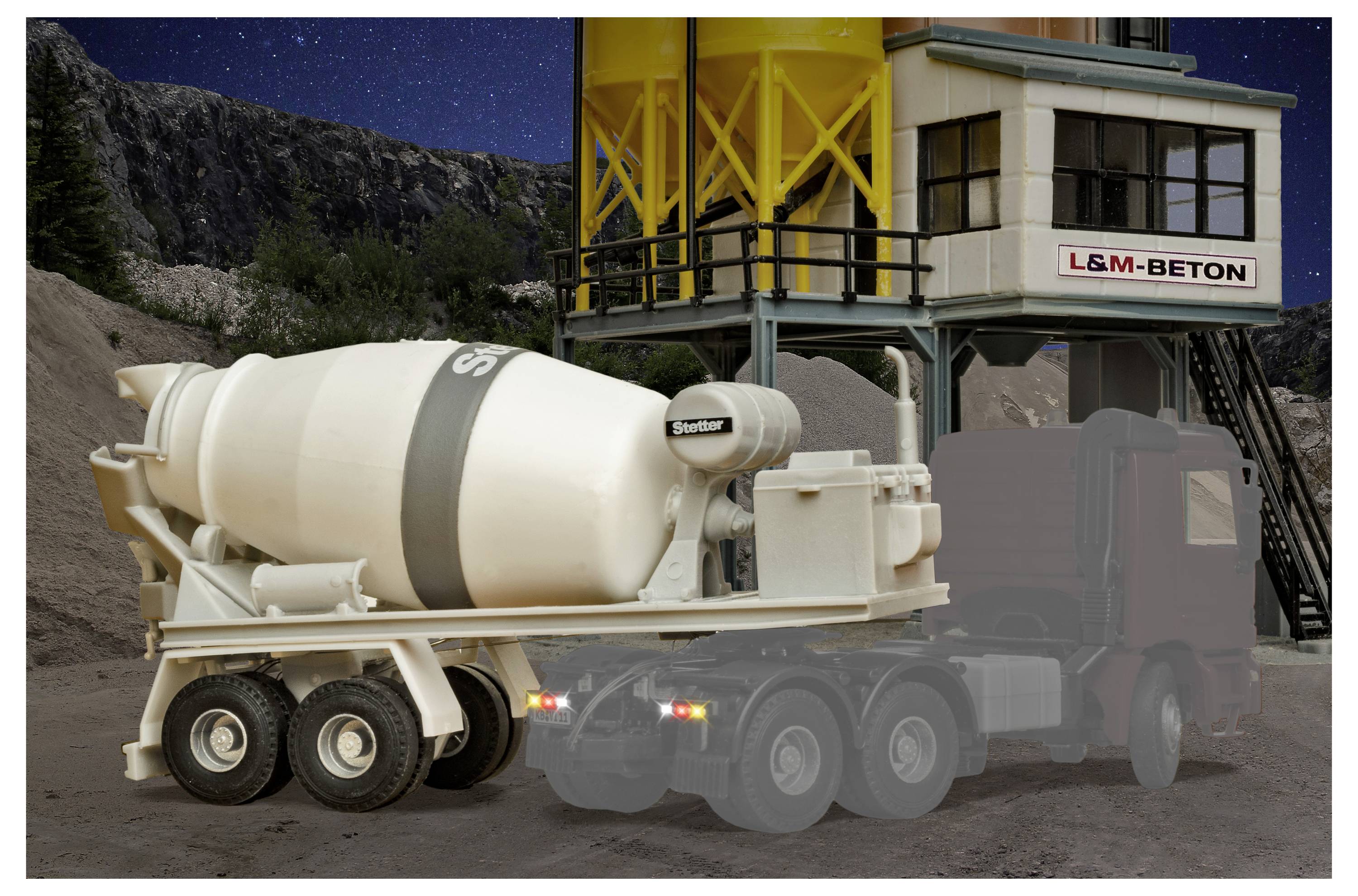Betoniera in un cantiere edile accanto a un edificio di impianto etichettato "L&M-BETON", con un grande tamburo di miscelazione e carrozzeria del camion parzialmente trasparente.