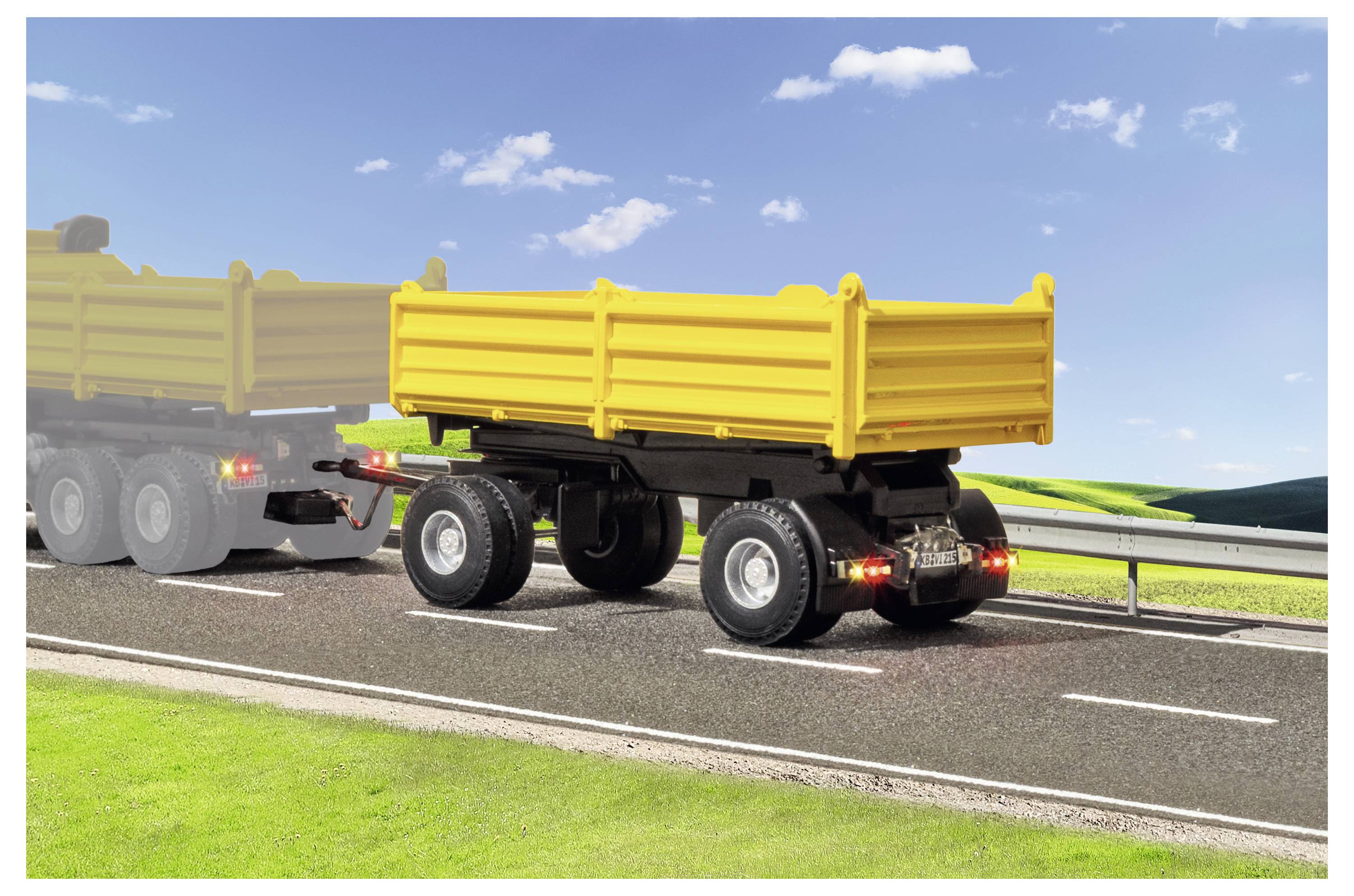 Rimorchio ribaltabile giallo trainato su un'autostrada, con un altro camion parzialmente visibile davanti e una barriera di sicurezza lungo la strada.