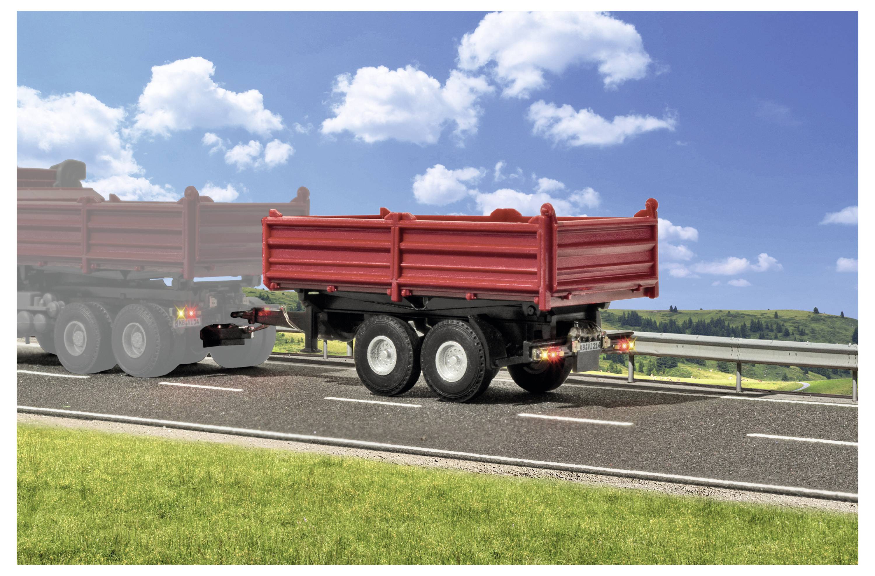 Rimorchio ribaltabile rosso trainato su un'autostrada, con una vaga sagoma di camion semi-articolato sfocata dietro sotto un cielo blu con nuvole.