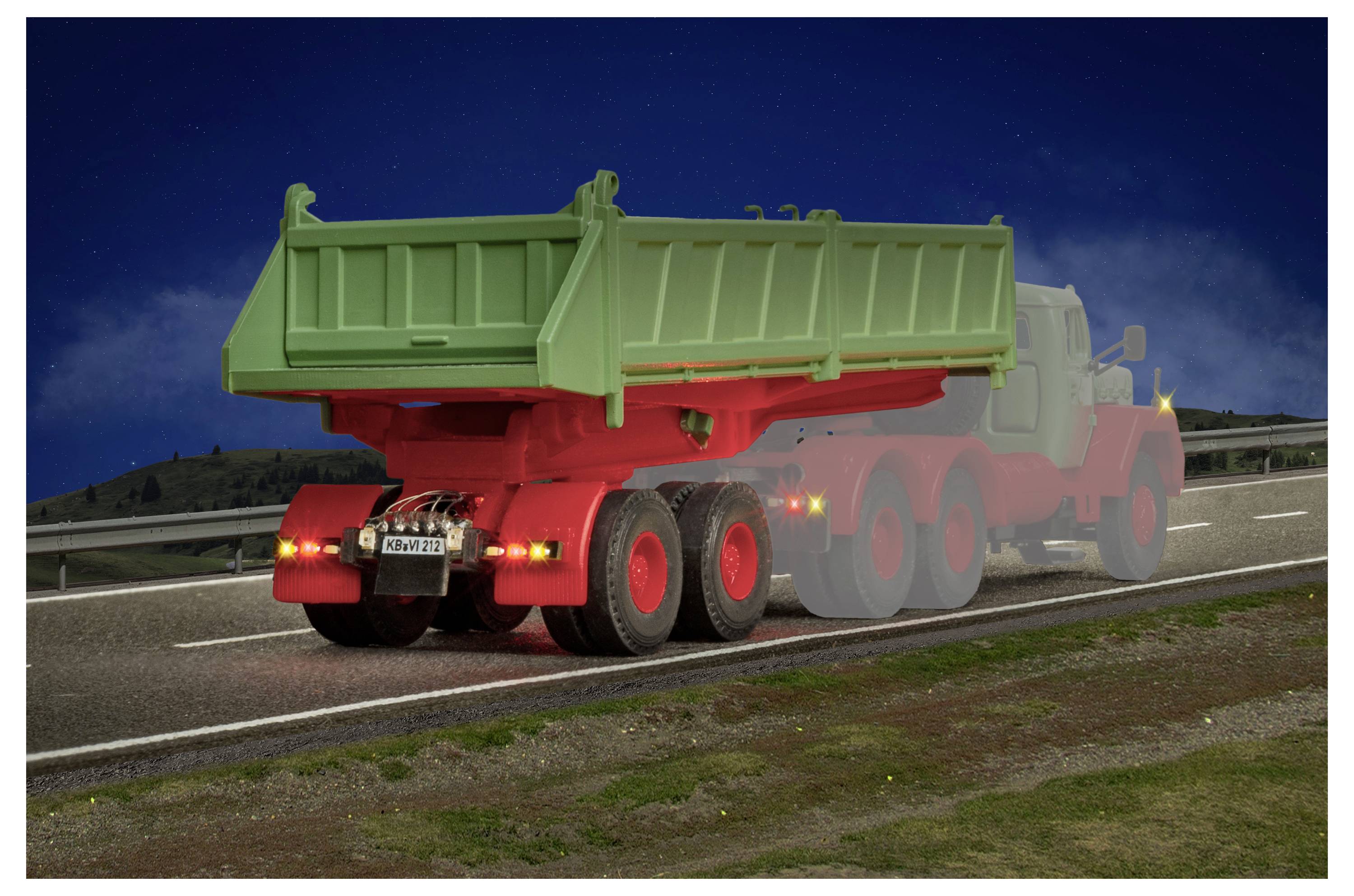 Vista posteriore di un camion ribaltabile verde e rosso che percorre un'autostrada di notte, con le luci posteriori visibili e una sfocatura di movimento che suggerisce velocità.