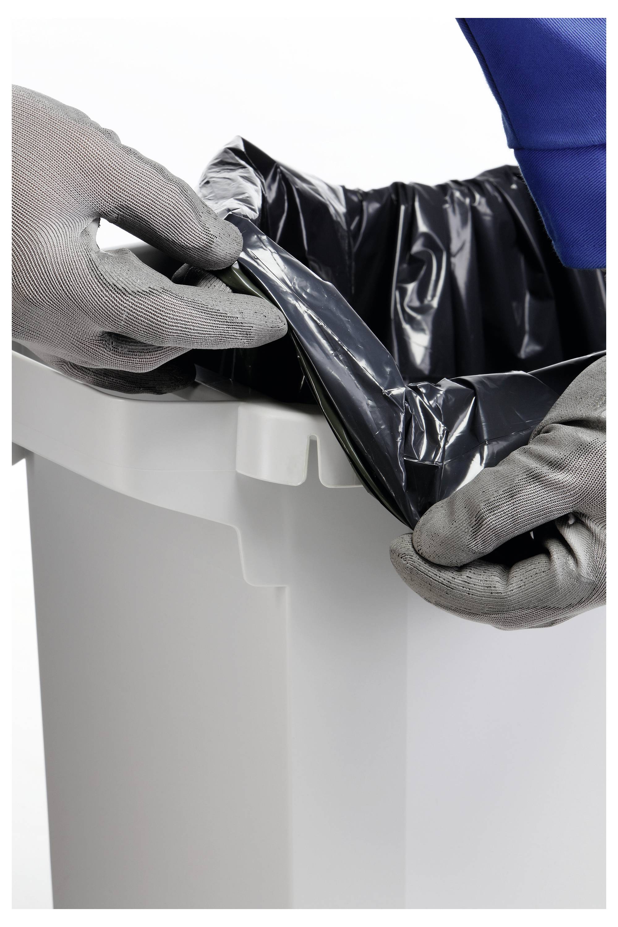 Le mani guantate rivestono un bidone della spazzatura bianco con un sacchetto di plastica nera per i rifiuti.