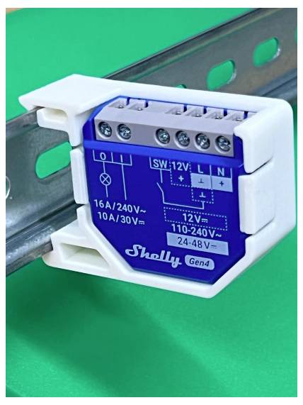 Modulo relè intelligente Shelly Gen4 montato su guida DIN, etichettato con morsetti di cablaggio e valori di tensione per il controllo elettrico domestico.
