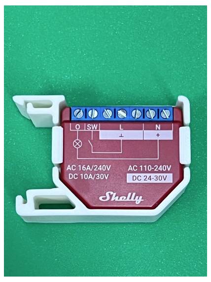 Modulo relè Shelly su sfondo verde, che mostra morsetti a vite etichettati O, SW, L e N con valori nominali di potenza CA 16A/240V, CC 10A/30V, CA 110-240V e CC 24-30V.