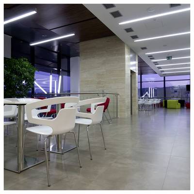 Moderna lounge con sedie e tavoli bianchi in una spaziosa e vuota hall interna o mensa con grandi finestre e luci a soffitto luminose.