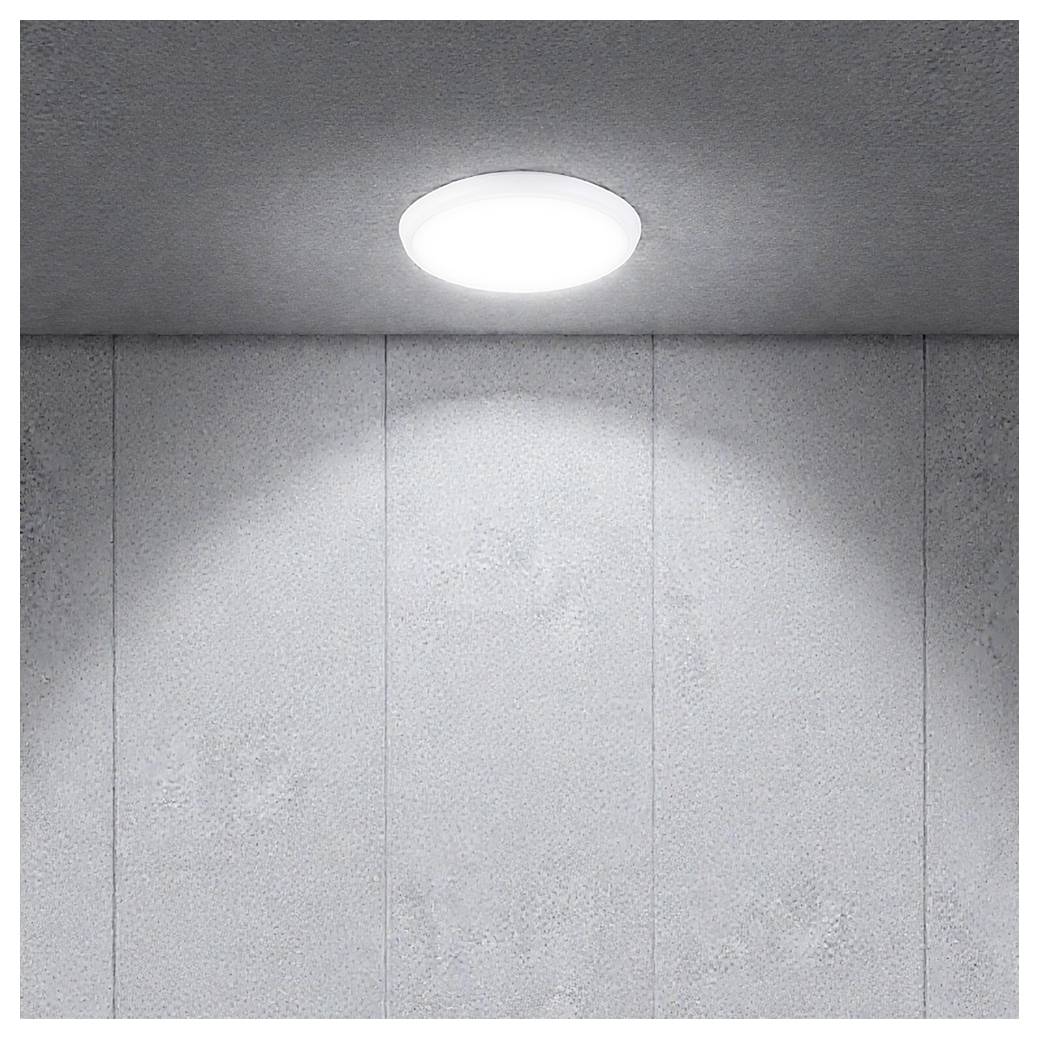 Lampada da soffitto rotonda su una parete rivestita di pannelli grigi, che emette una luce soffusa in un interno altrimenti sobrio.
