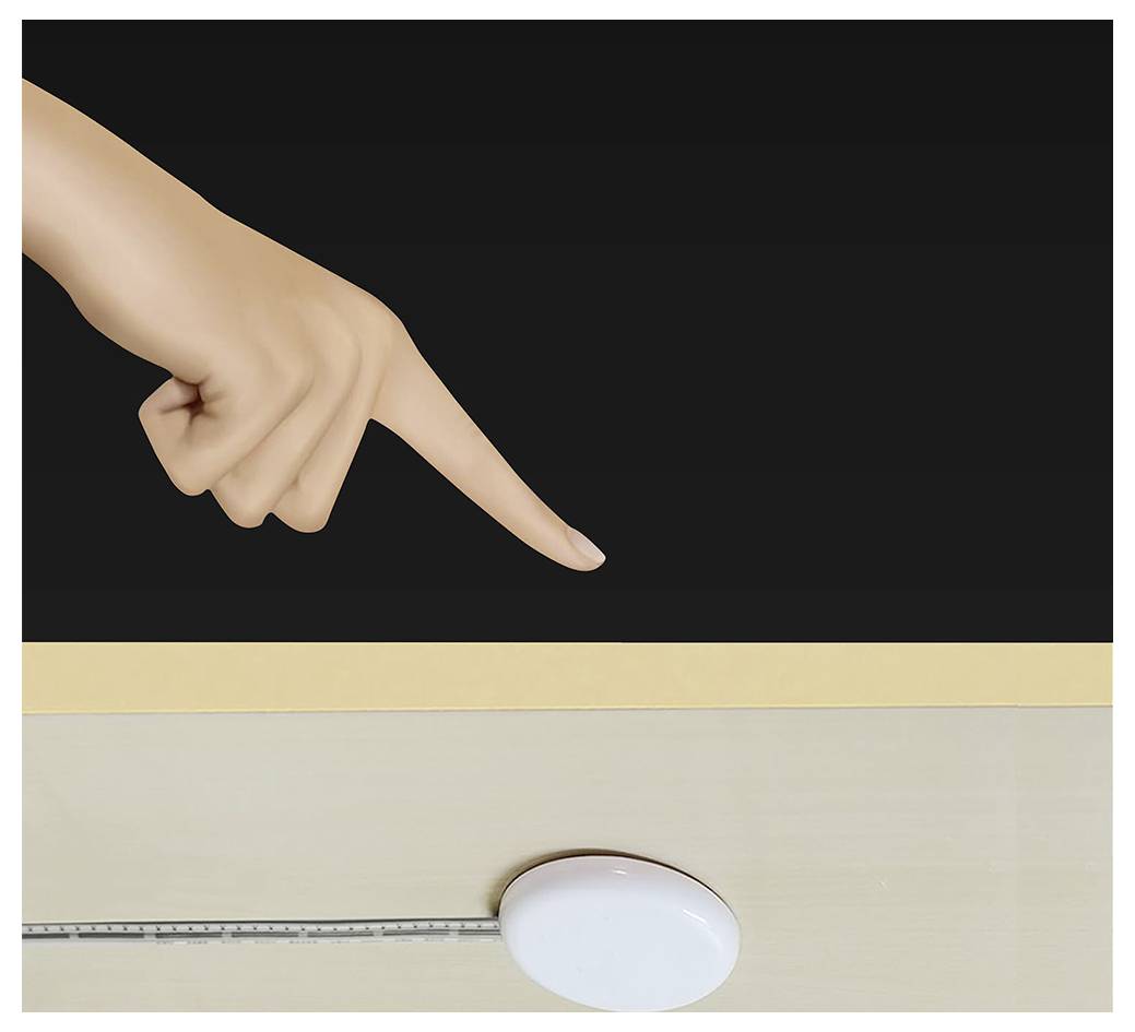 Una mano punta verso un oggetto ovale bianco su una superficie chiara, con un righello lungo il bordo inferiore contro uno sfondo scuro.