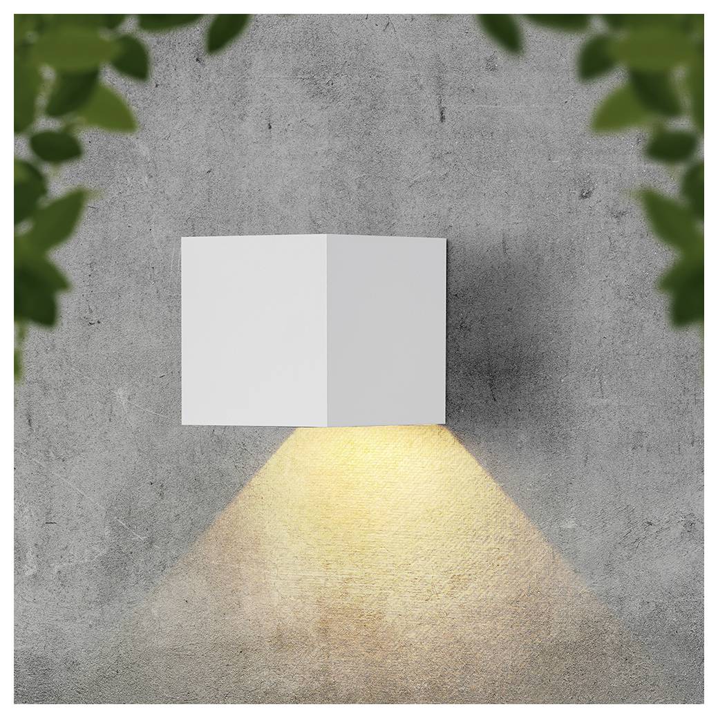 Lampada da parete moderna bianca che proietta un caldo fascio di luce triangolare su una parete grigia in cemento, incorniciata da foglie verdi sfocate agli angoli.
