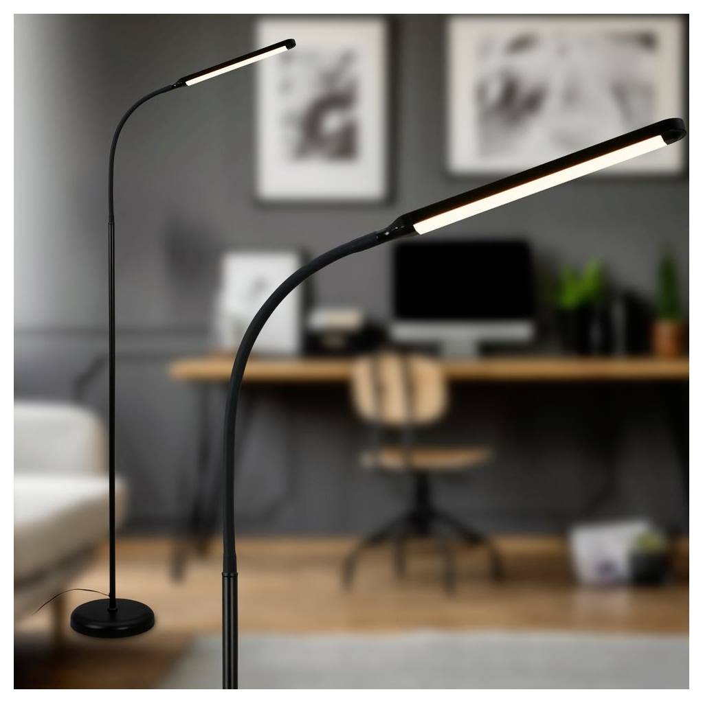 Due lampade da terra LED moderne nere in una sfocata home office, con una scrivania, una sedia, un monitor per computer e opere d'arte alle pareti sullo sfondo.