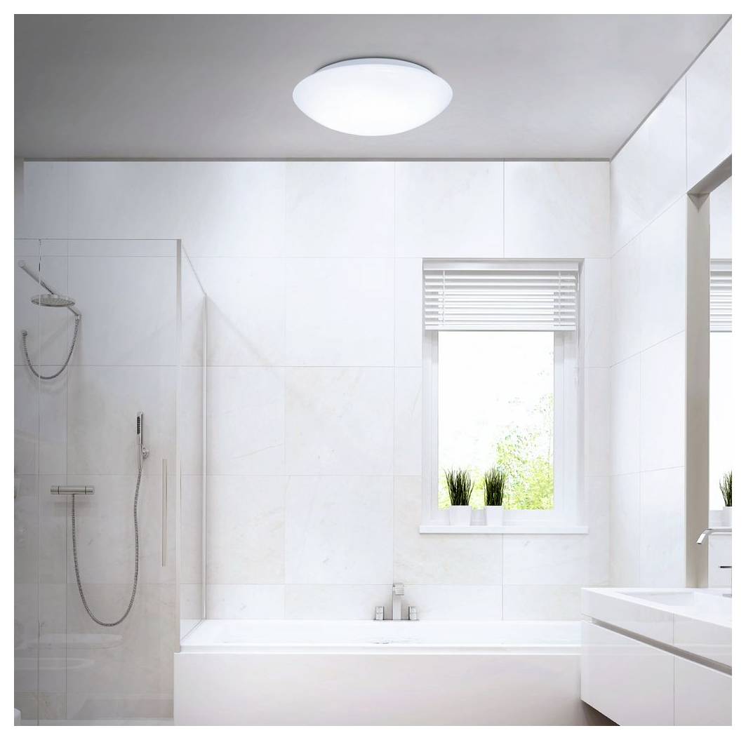 Bagno moderno e luminoso con una vasca da bagno, doccia in vetro, lavandino e finestra con tende veneziane e piante in vaso.