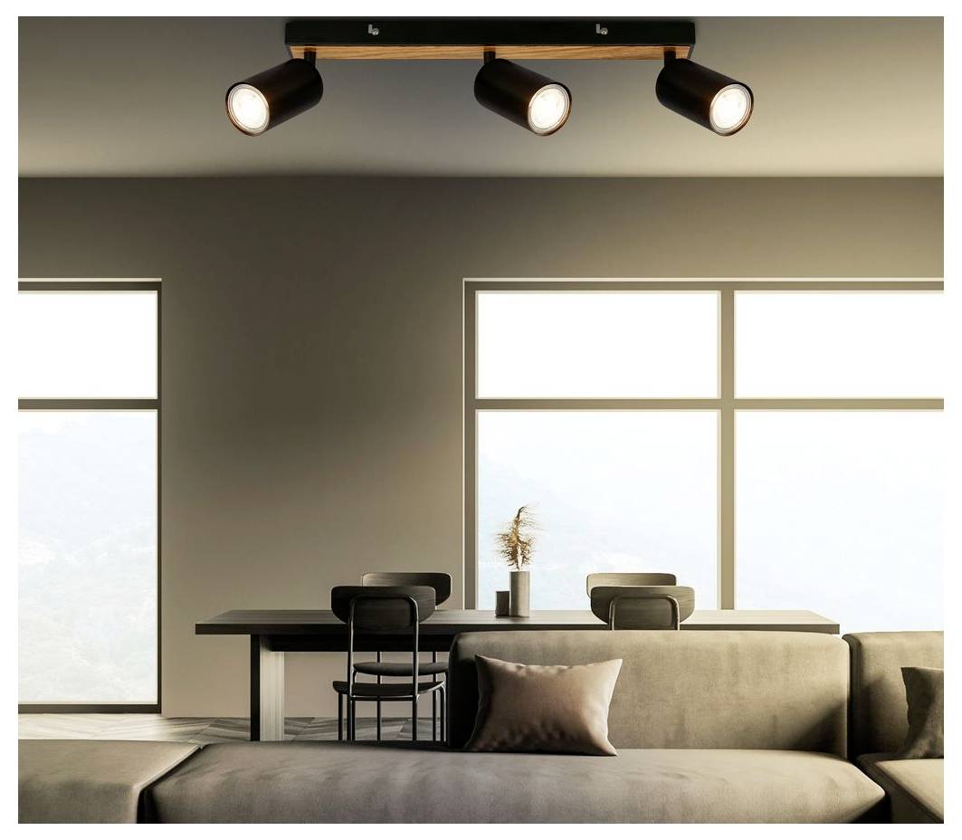 Soggiorno moderno con divano, tavolo da pranzo e sedie, grandi finestre e tre faretti a soffitto che illuminano lo spazio.