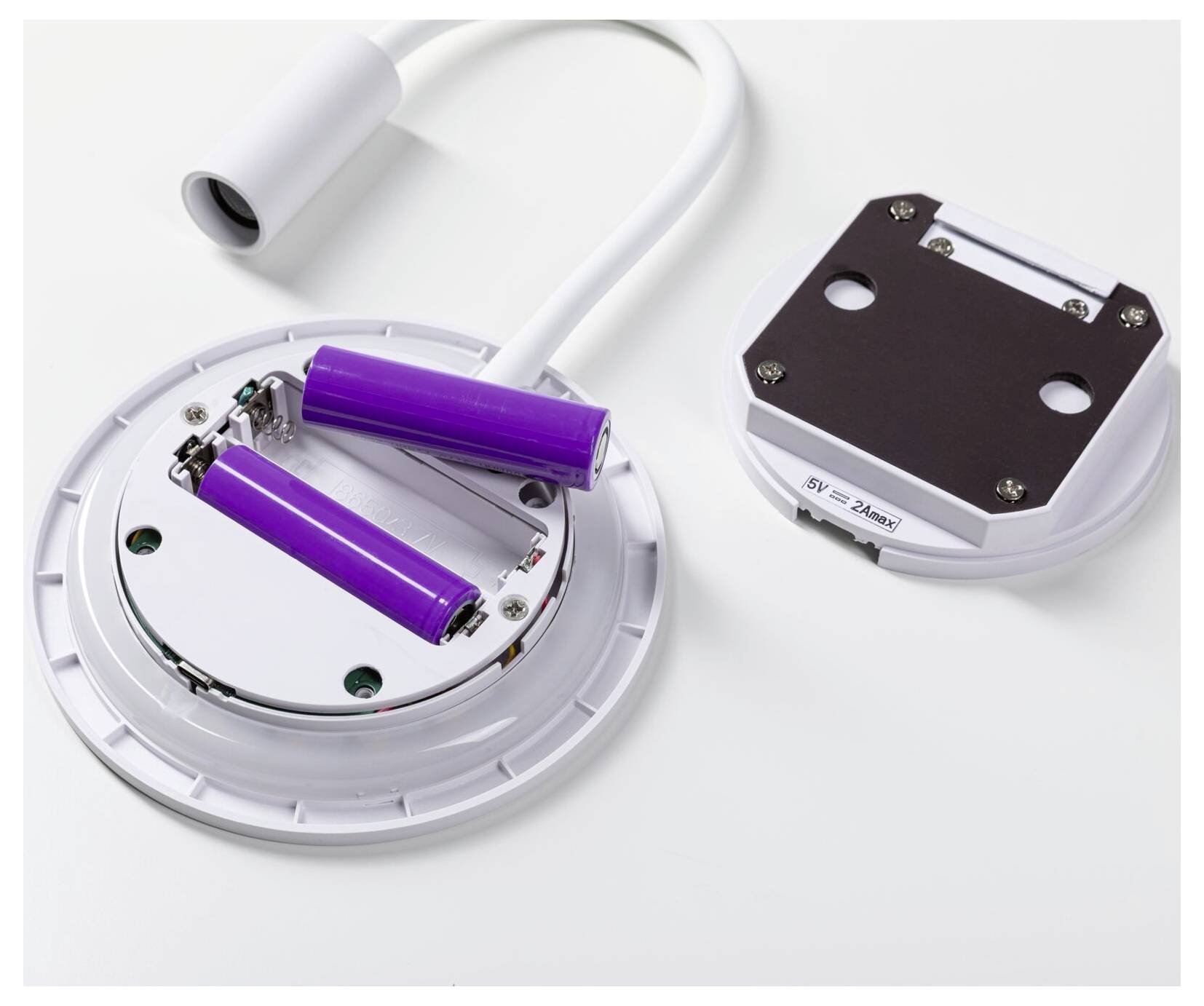 Dispositivo aperto alimentato a batteria con due batterie cilindriche viola, un cavo bianco e un coperchio staccato su uno sfondo bianco.