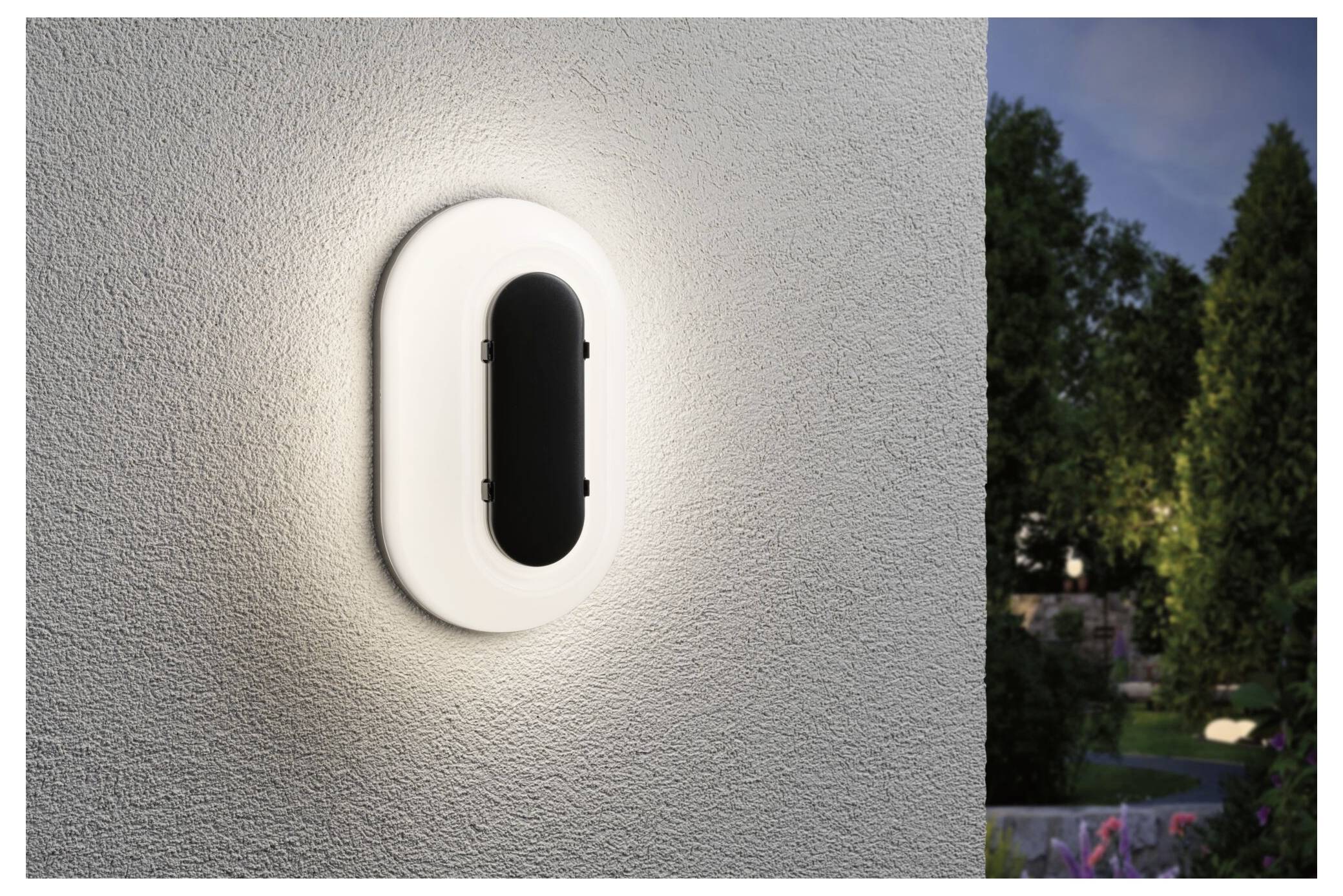 Applique murale ovale moderna su una parete esterna strutturata, che brilla dolcemente accanto a una scena esterna al tramonto.