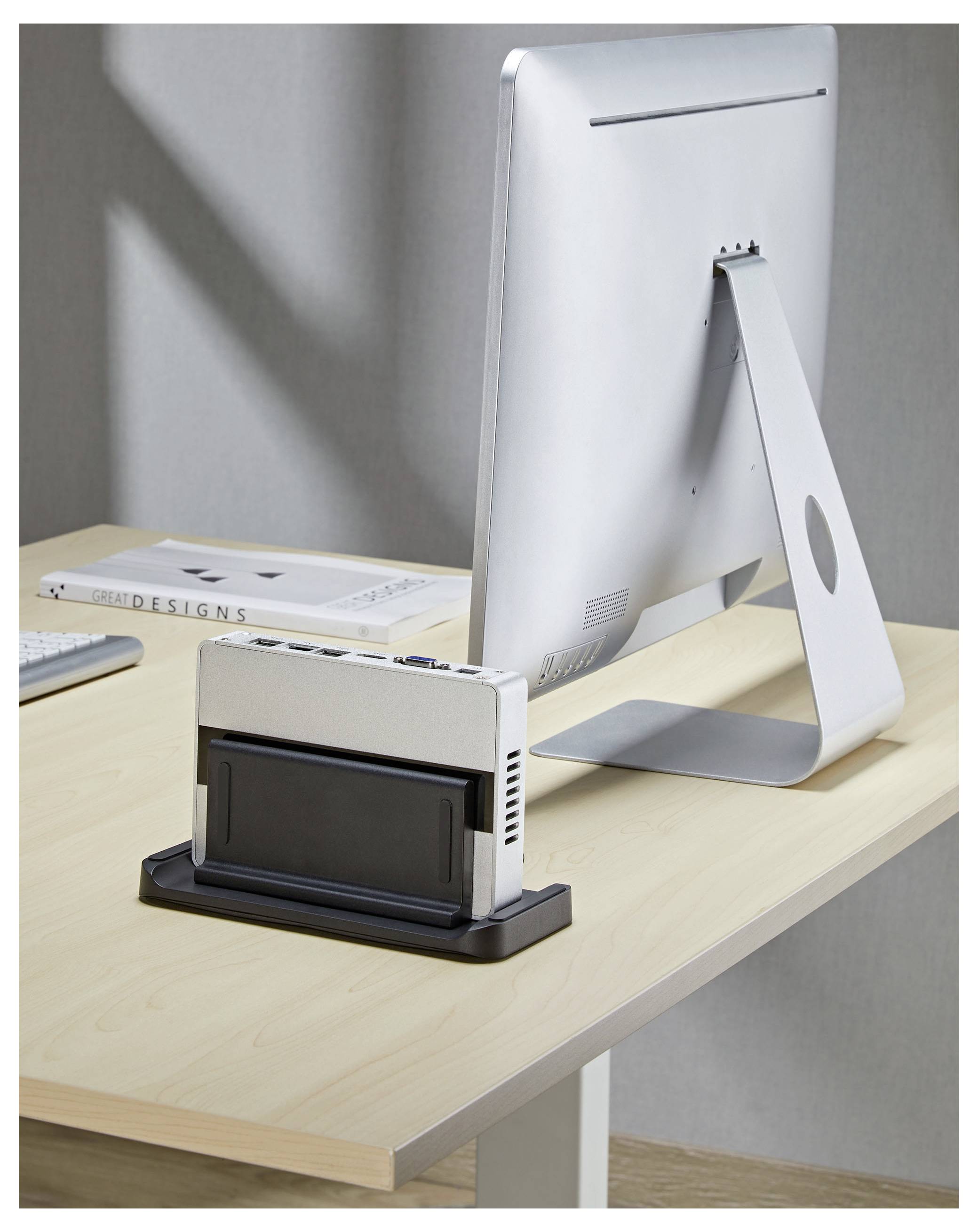 Setup moderno da desktop con un iMac su un tavolo in legno e una dock accessori compatta o un adattatore in primo piano.