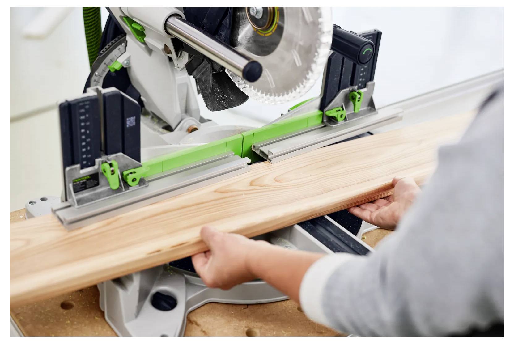 Persona che utilizza una sega a spigoli per tagliare una tavola di legno, con morsetti di sicurezza che tengono il legno in posizione.