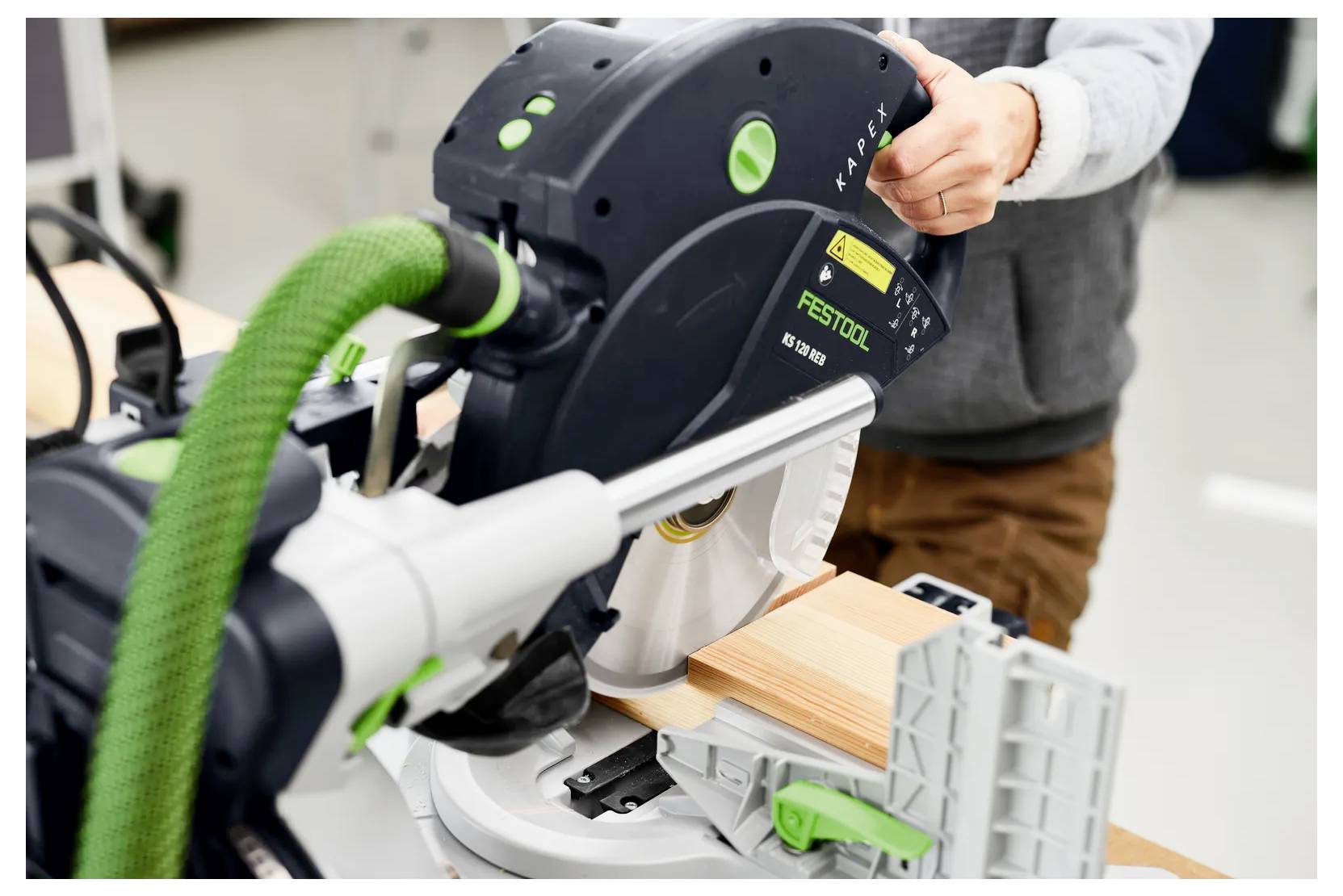 Una persona che utilizza una sega circolare Festool per tagliare una tavola di legno in un laboratorio.