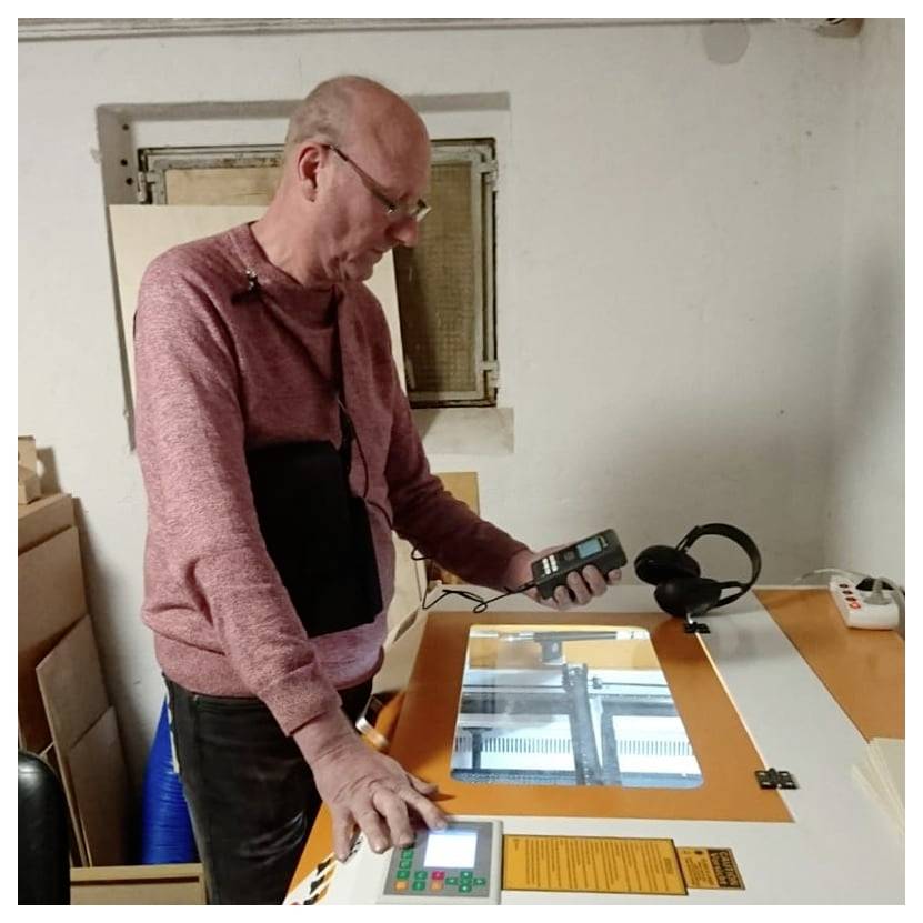 L'uomo utilizza un dispositivo portatile su un tavolo di ispezione illuminato in un laboratorio, osservando lo schermo mentre utilizza un pannello di controllo.