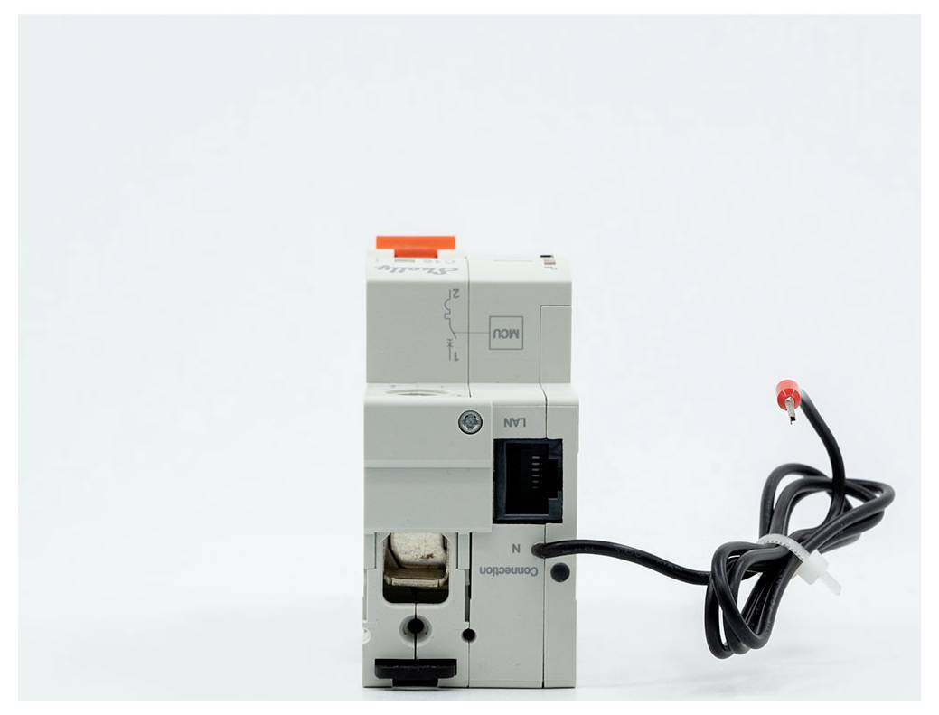 Interruttore di circuito elettrico grigio con una sonda cablata nera e una pinza di prova rossa collegata su uno sfondo bianco semplice.