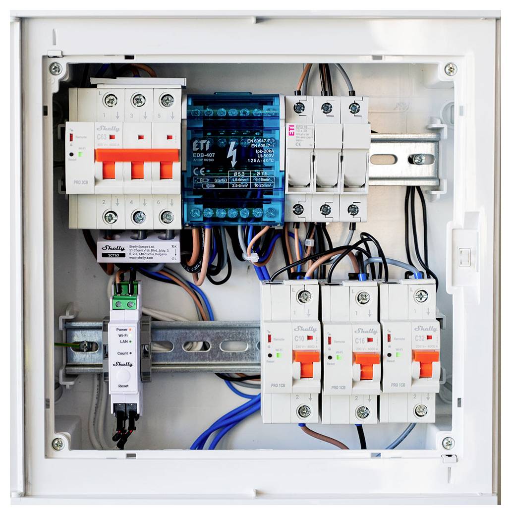 Un pannello di distribuzione elettrica con molteplici interruttori automatici, relè e cablaggio montati all'interno di un involucro in metallo bianco.