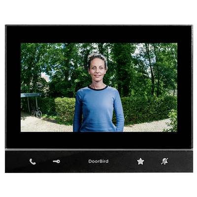 Schermo videocitofono DoorBird che mostra una donna in piedi all'aperto davanti a alberi e un sentiero.