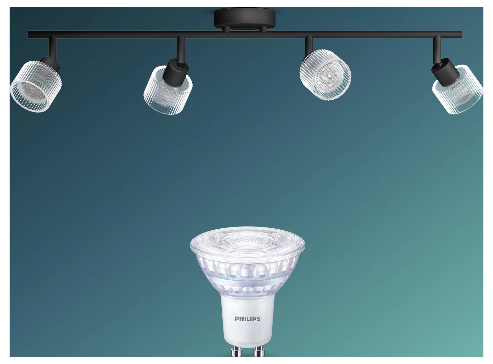Una lampadina faretto Philips sotto quattro faretti su binario montati a soffitto su uno sfondo teal.