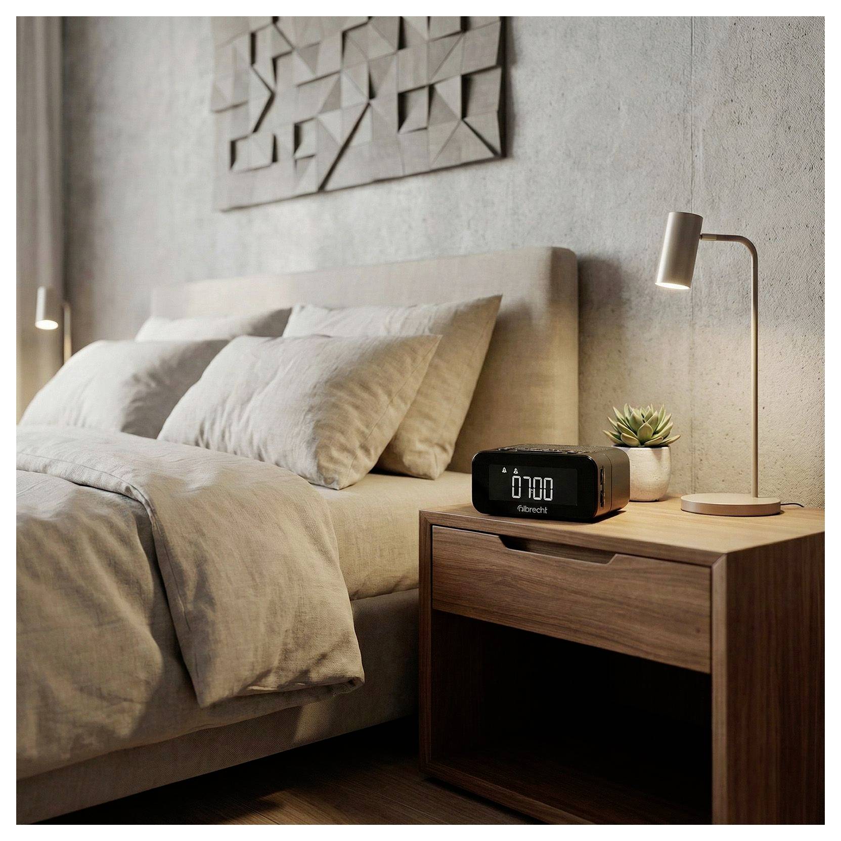 Camera da letto moderna con un letto rifatto, comodino in legno, lampada, pianta e sveglia digitale sul tavolo notturno.