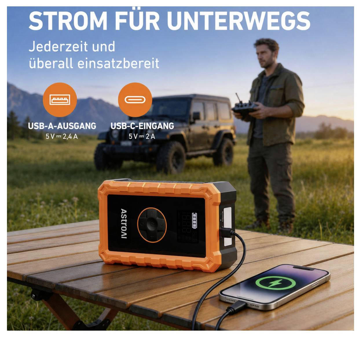 Stazione di energia portatile su un tavolo da picnic che carica un telefono, con testo tedesco "STROM FÜR UNTERWEGS" e etichette di uscita USB-A/USB-C; uomo e veicolo fuoristrada sullo sfondo.