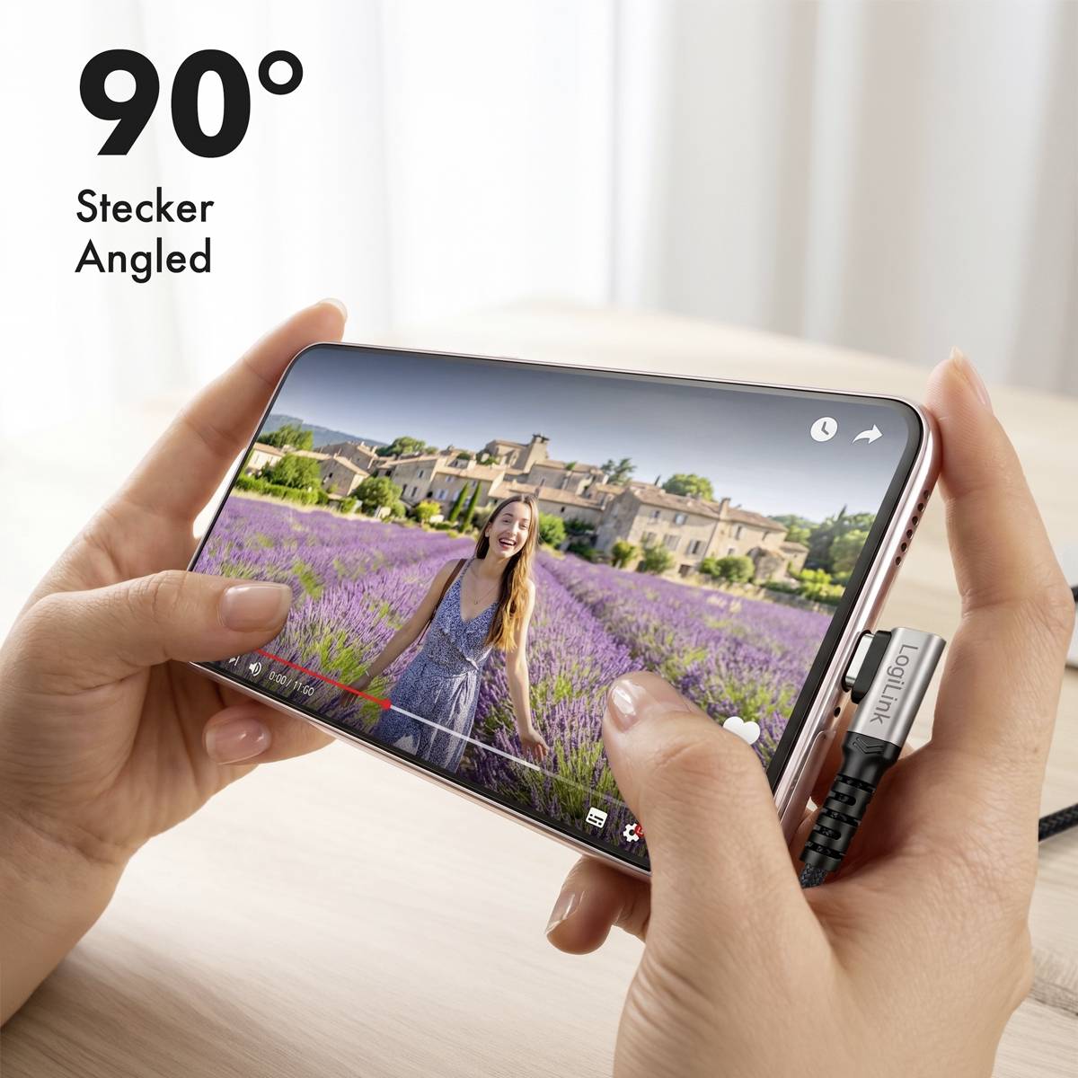 Mani che tengono uno smartphone in orientamento orizzontale con un cavo di ricarica angolato a 90° inserito mentre un video viene riprodotto sullo schermo.