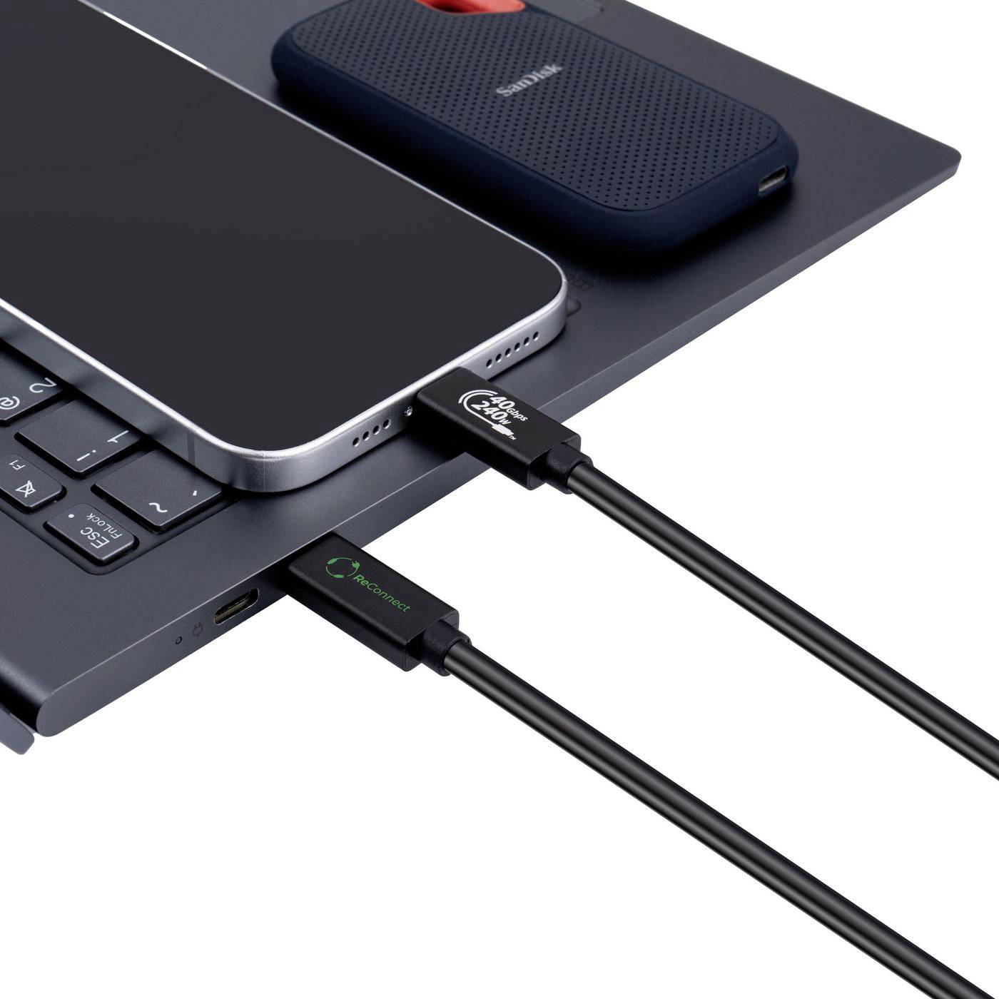 Laptop con uno smartphone collegato tramite cavi USB, mostrato insieme a un'unità esterna portatile sulla superficie del laptop.