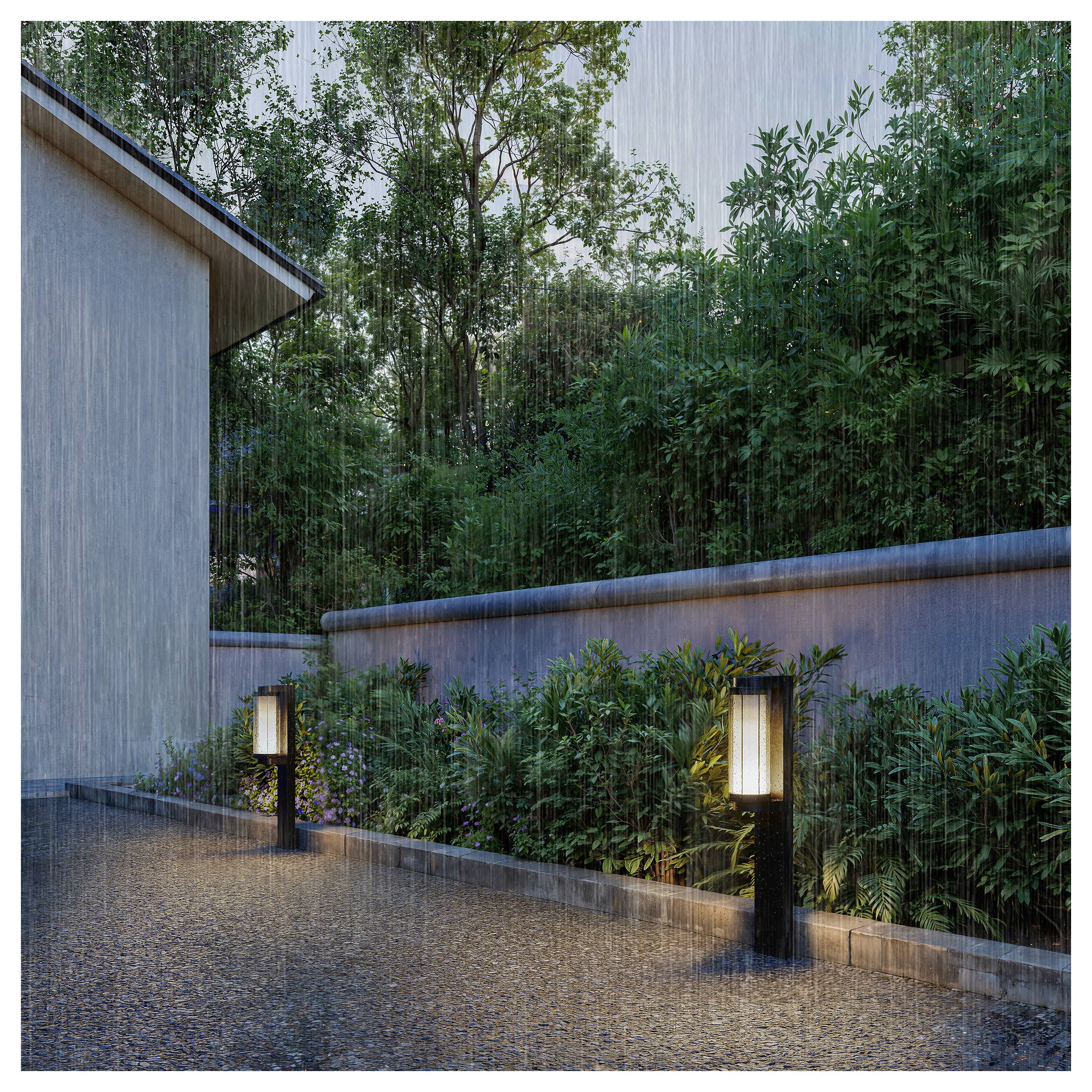 La pioggia cade su un moderno corridoio di cortile con lanterne illuminate, un muro bianco e un paesaggistica verde fitta.