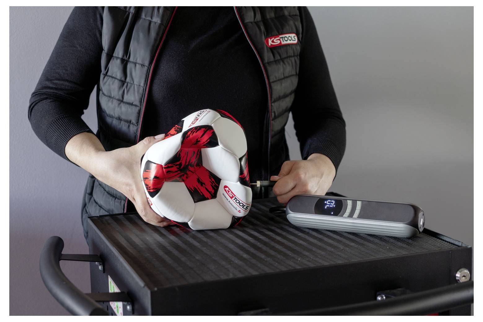 Una persona che utilizza un dispositivo portatile per ispezionare un pallone da calcio su un banco di lavoro, probabilmente controllando la sua rotondità o l'equilibrio.